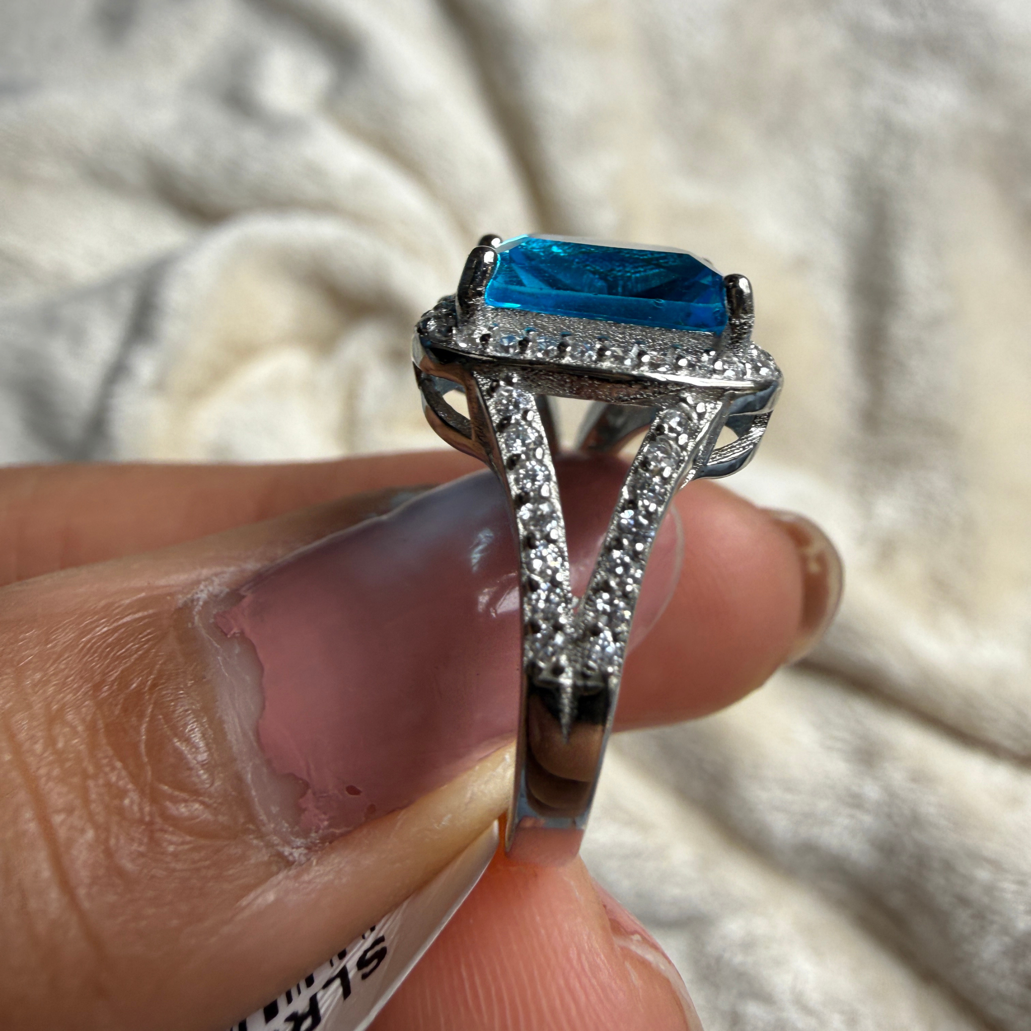 Blue emerald-cut gemstone and lab-grown diamond halo ring by Kiashaa Jewellery.
