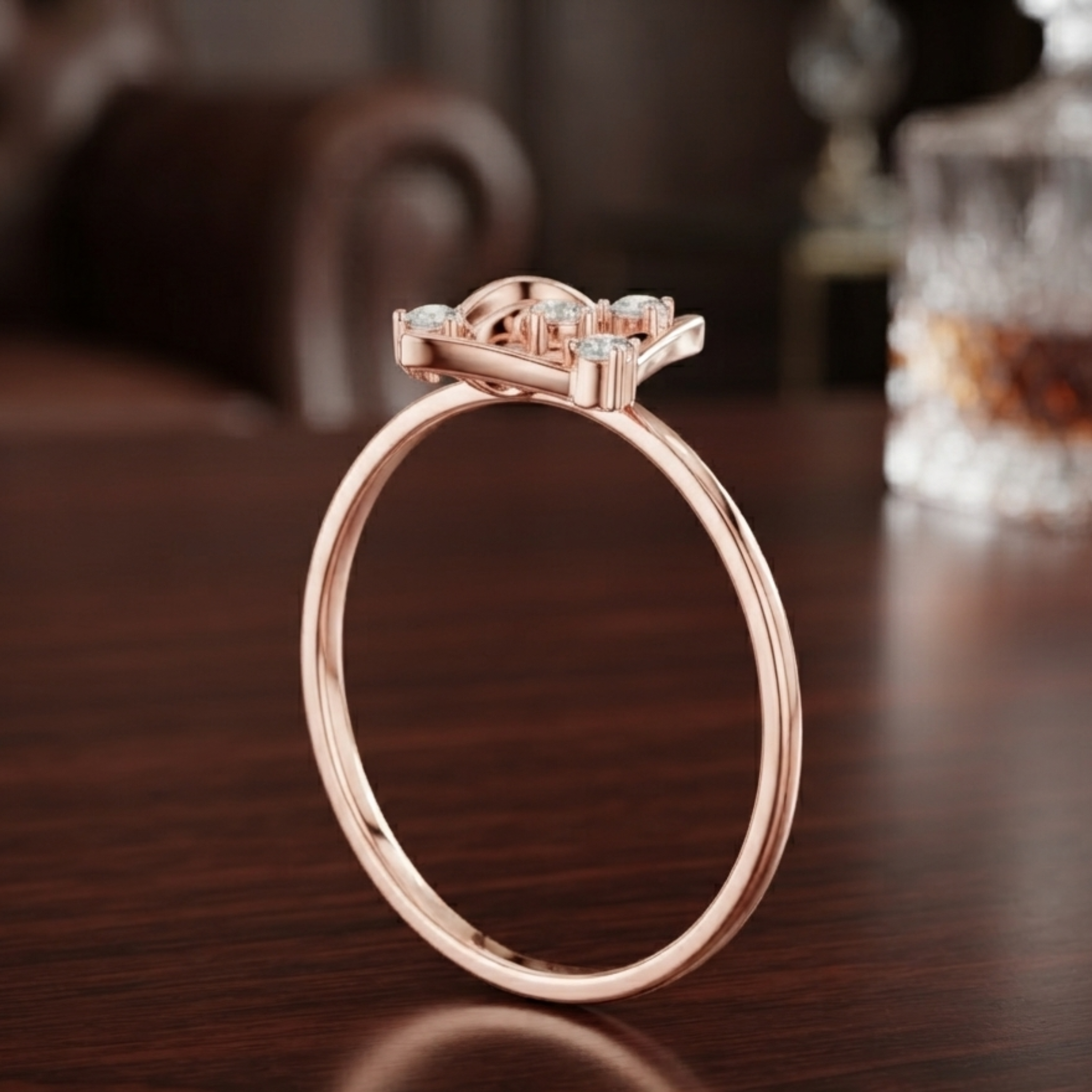 A rose gold ring with a bow-like top set with small clear gemstones, standing on a dark wooden table.