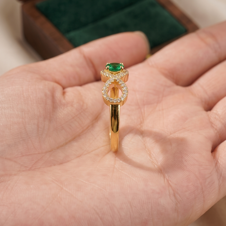 Luxury infinity ring featuring a 0.20 carat round green center diamond.