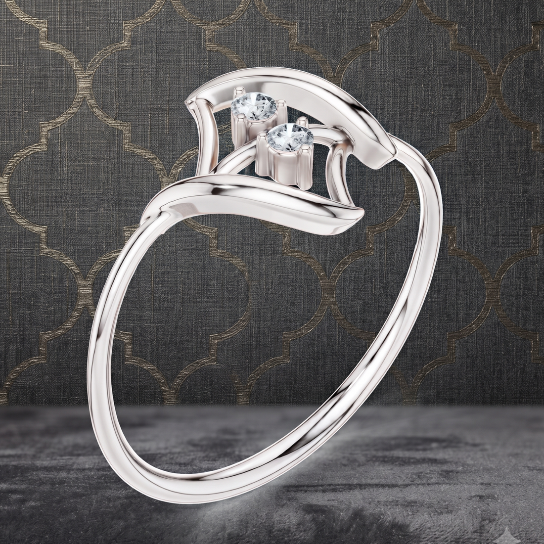 A polished silver-tone ring with two clear gemstones, shown floating against a dark textured background with a subtle gold trellis pattern.