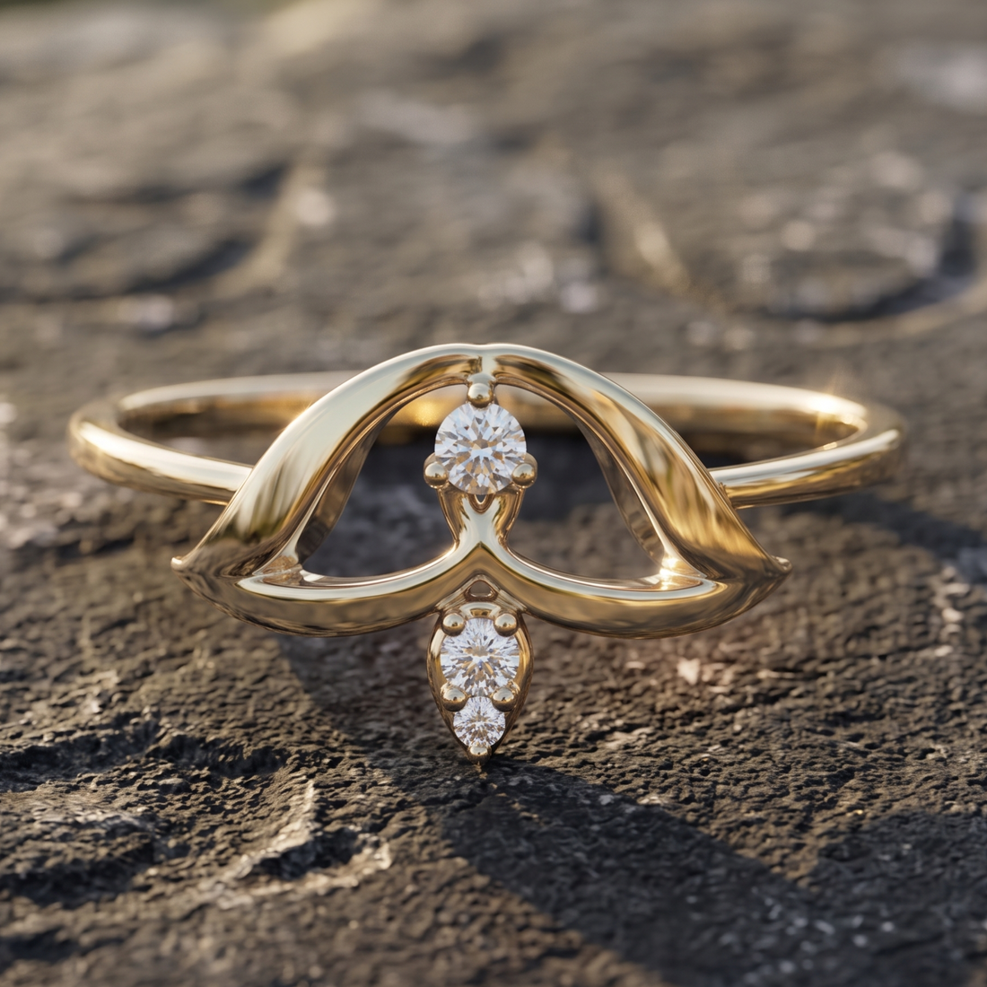 A gold ring with a sculptural, flowing openwork design and two small clear gemstones, photographed resting on a textured dark stone surface.