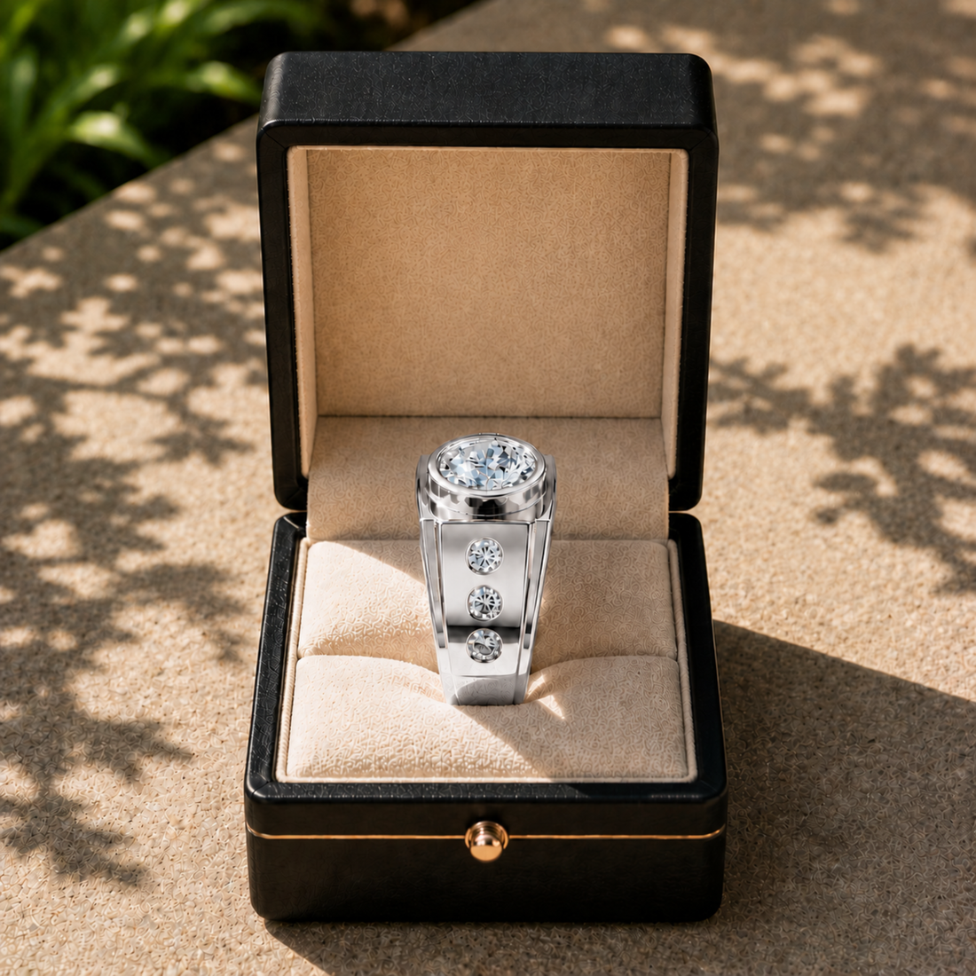 A silver-toned ring with a large round clear gemstone and three smaller side stones, displayed in an open black jewelry box on a sunlit stone surface.