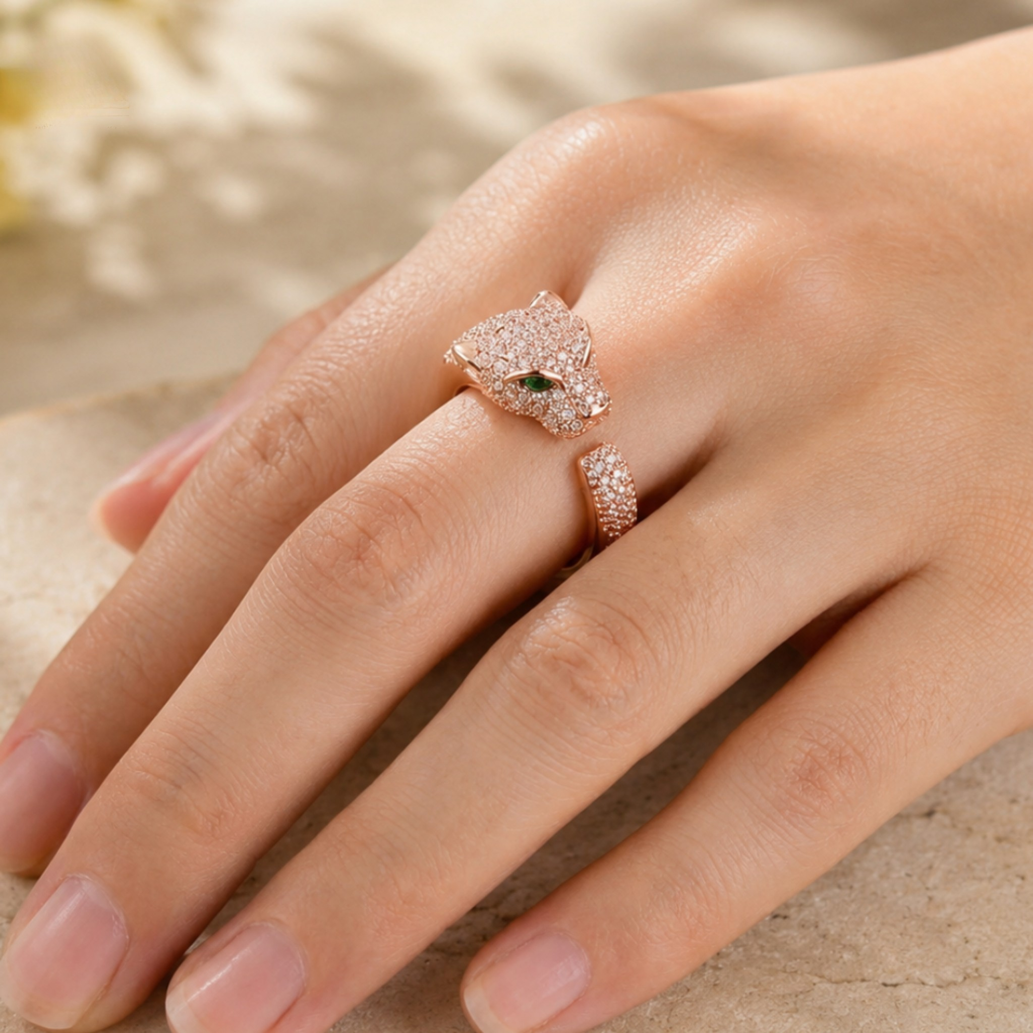 A close-up of a hand wearing a rose gold ring set with small clear stones and a tiny green accent stone, alongside a matching rose gold band.