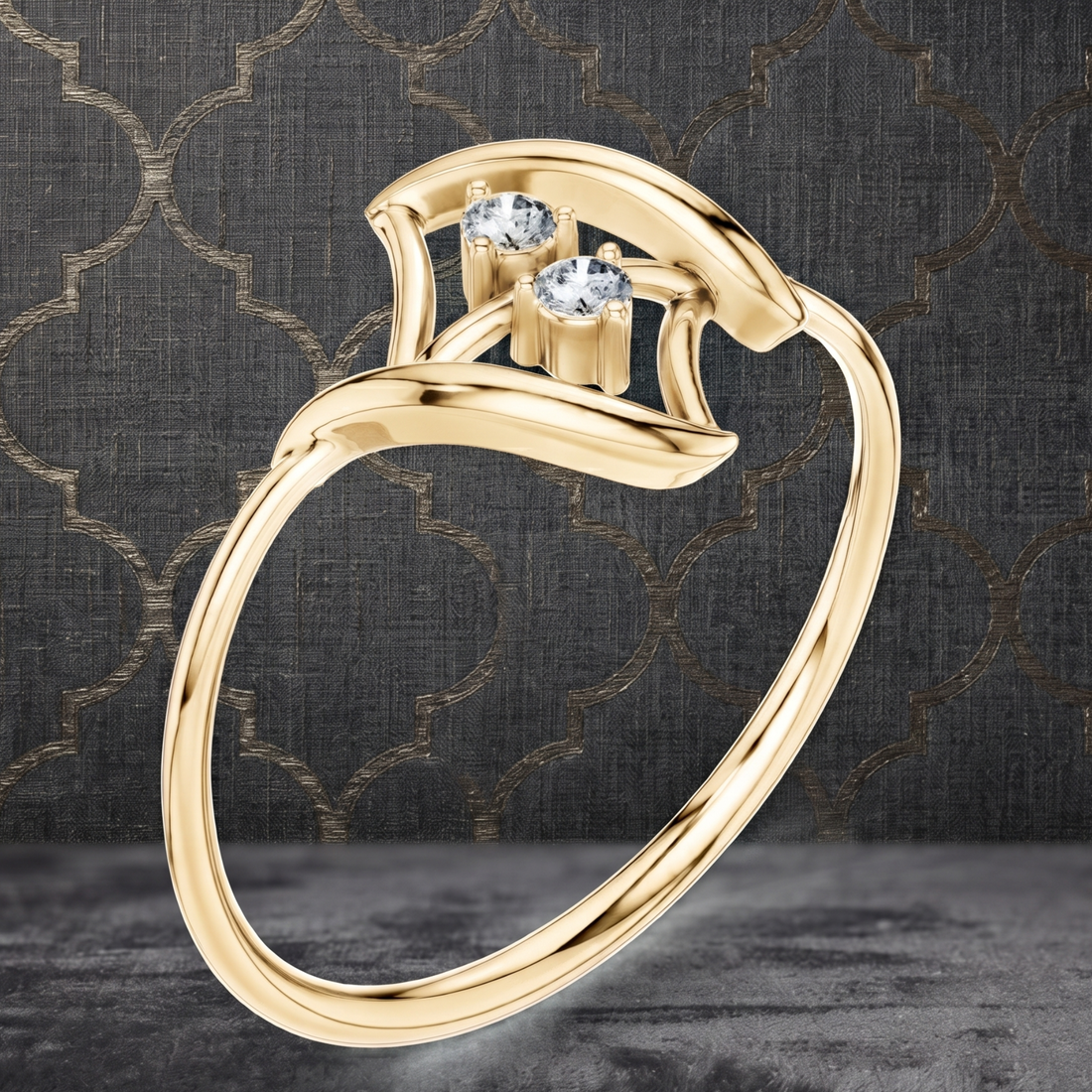A gold ring with a curved, openwork band and two small clear gemstones at the top, shown on a dark patterned background.