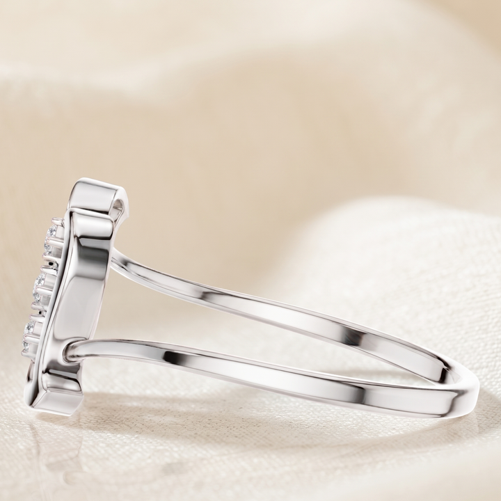 A silver ring with a rectangular pavé diamond setting, shown in a close-up studio shot on a soft beige fabric background.