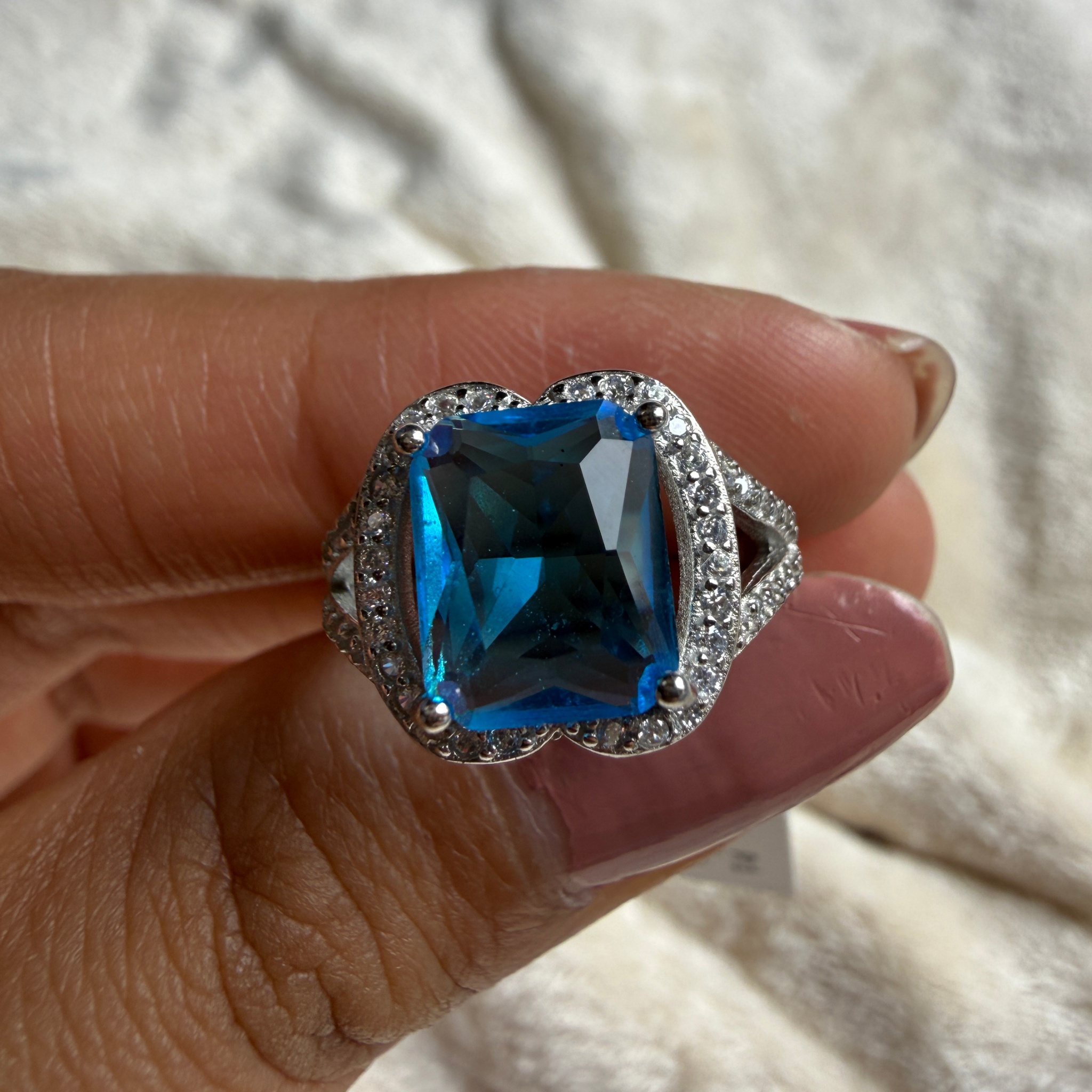Blue emerald-cut gemstone and lab-grown diamond halo ring by Kiashaa Jewellery.