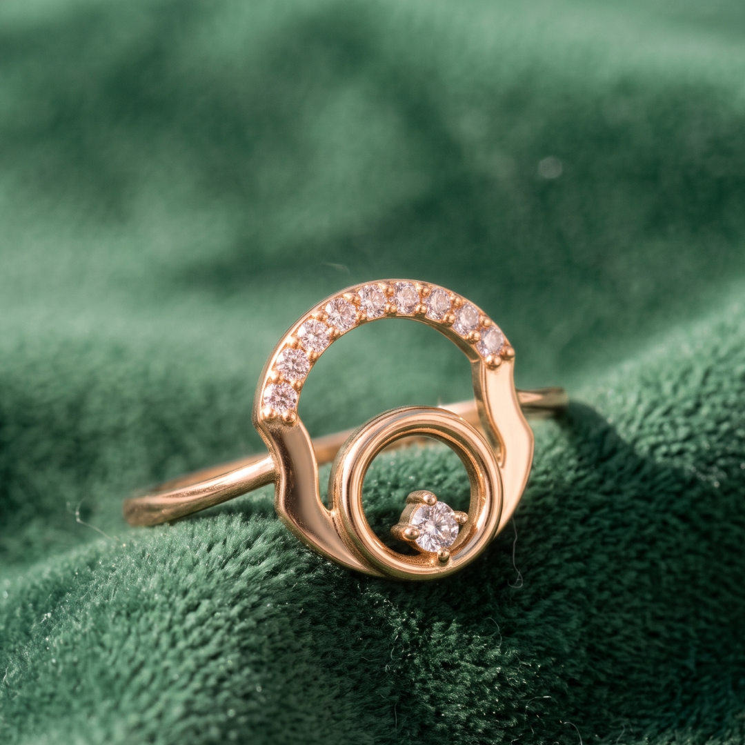 A rose gold ring with a double-ring design, one of which is adorned with small clear stones, resting on a textured green velvet surface.