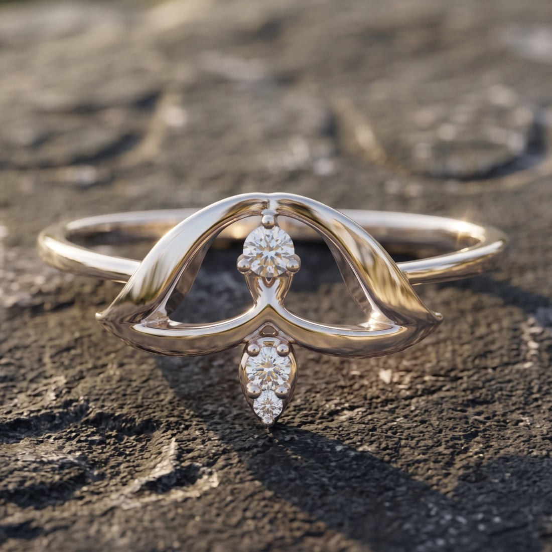 A polished yellow gold ring with a sculptural, flowing openwork design and small diamond accents, resting on a textured dark stone surface.