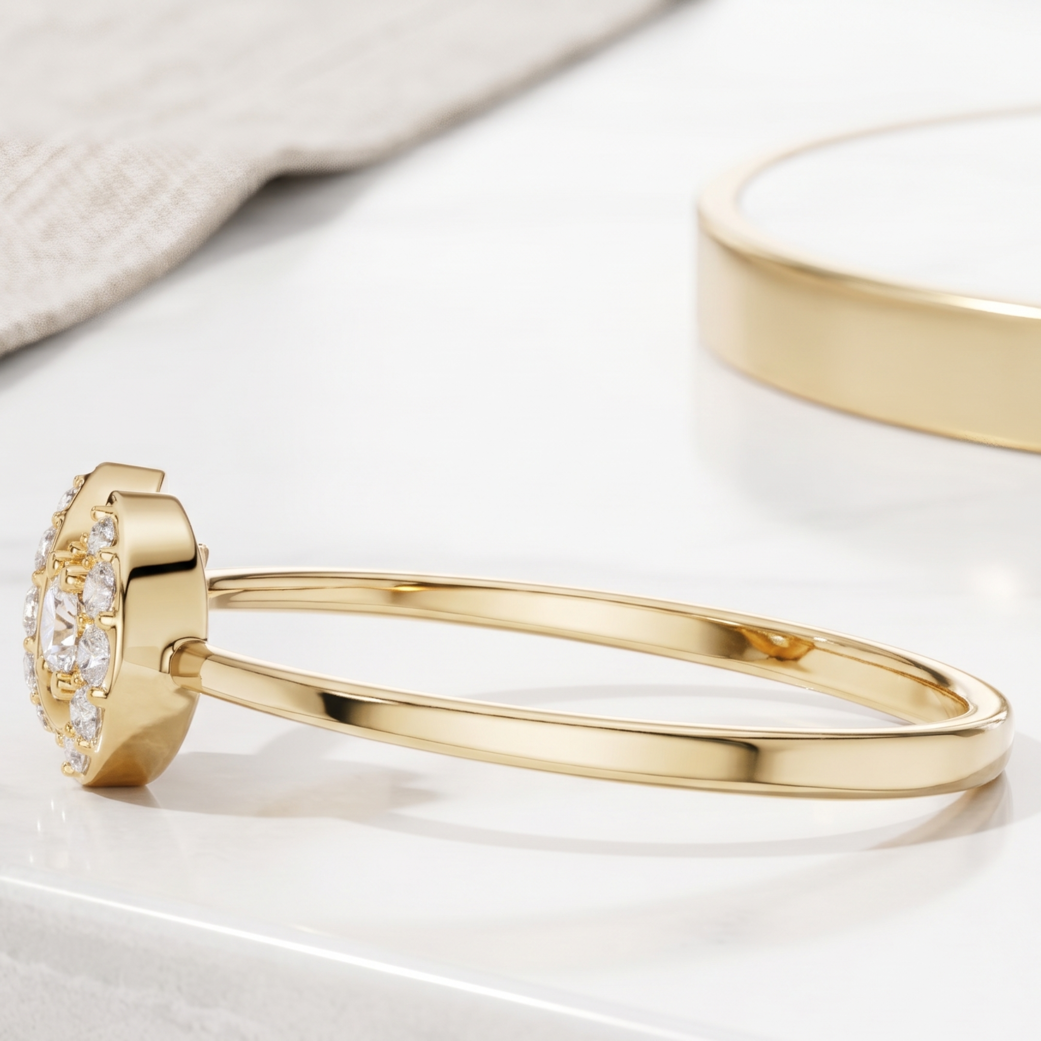 A polished gold bangle bracelet with a decorative floral cluster setting on one end, shown on a clean white surface with a soft-focus second bracelet in the background.
