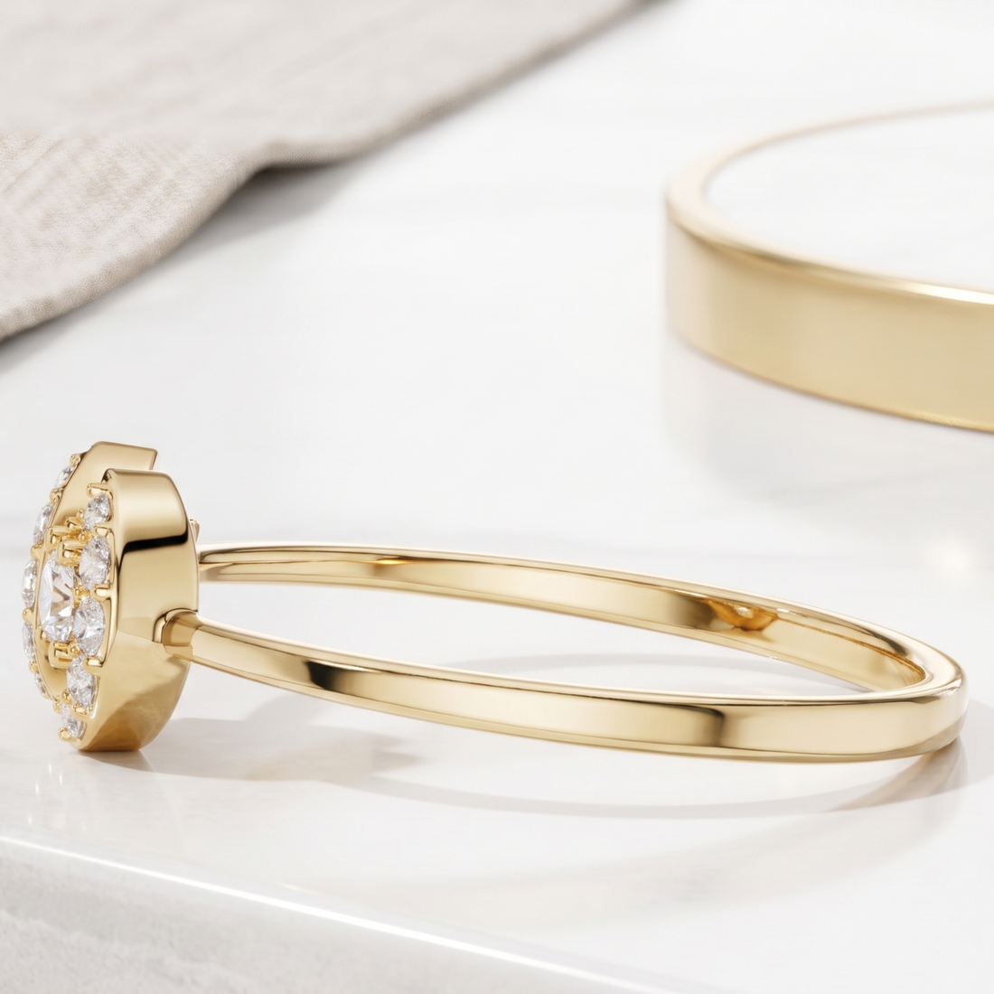 A polished gold bangle bracelet with a decorative floral cluster setting on one end, shown on a clean white surface with a soft-focus second bracelet in the background.