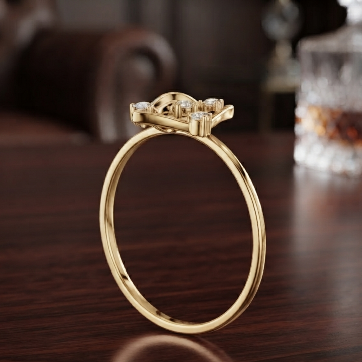 A yellow gold ring with a decorative three-stone crown and clear gemstones, displayed on a dark wooden table.