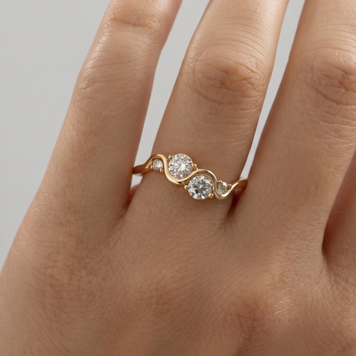 A gold ring with three round-cut clear gemstones set on a person's finger, shown in a close-up shot.