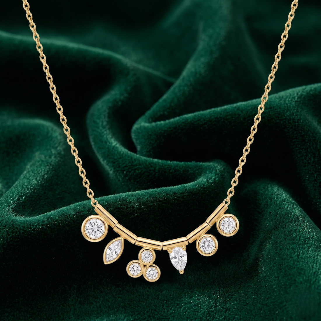 A gold necklace with a curved bar and multiple clear gemstones, displayed on a dark green velvet fabric background.