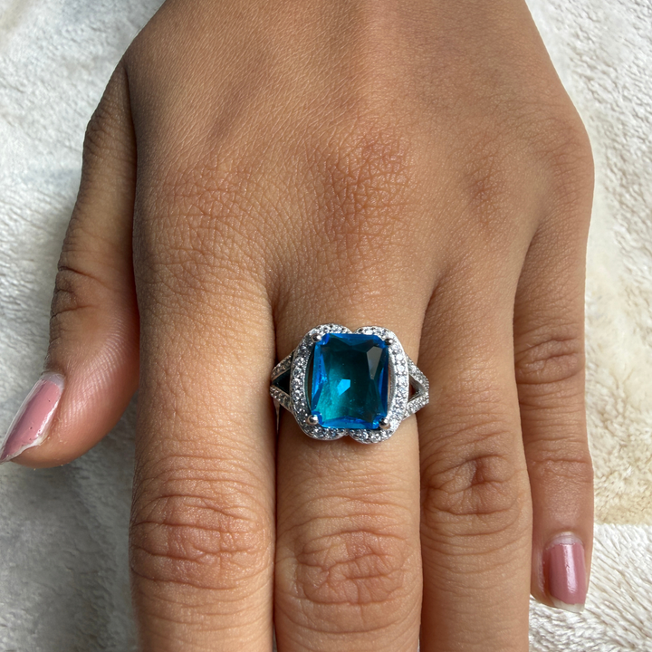 Blue emerald-cut gemstone and lab-grown diamond halo ring by Kiashaa Jewellery.