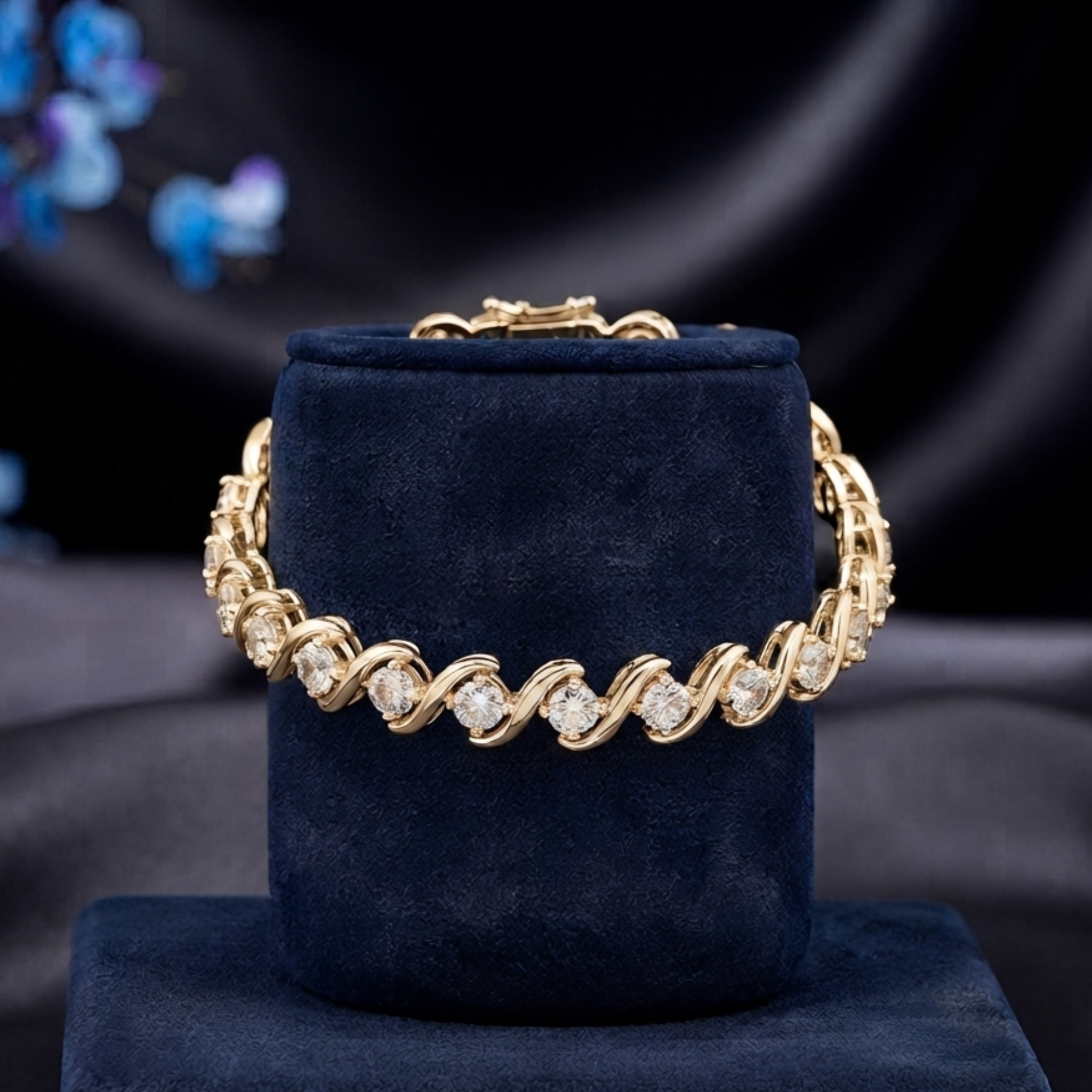 A gold-tone tennis bracelet with clear round-cut stones, displayed on a dark navy velvet jewelry stand against a dark draped fabric background.