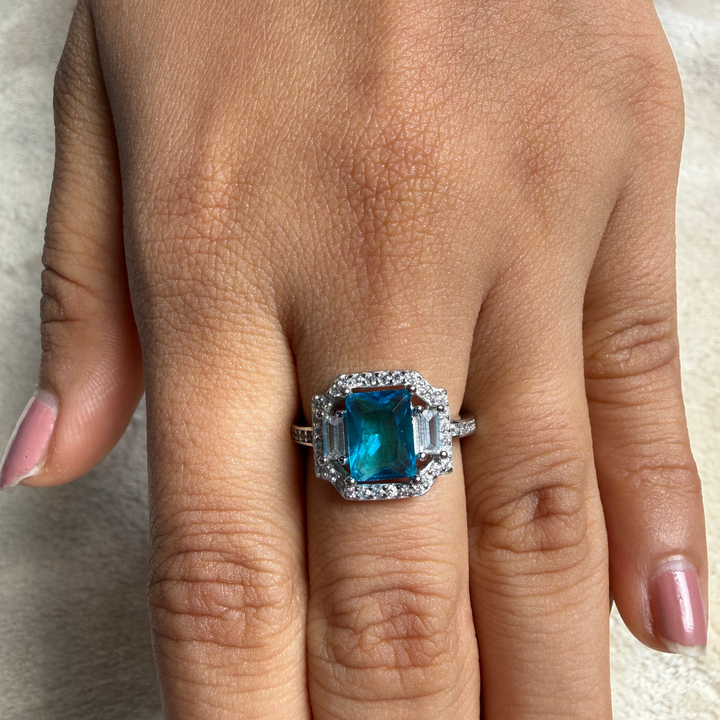 Blue emerald-cut gemstone and lab-grown diamond halo ring by Kiashaa Jewellery.