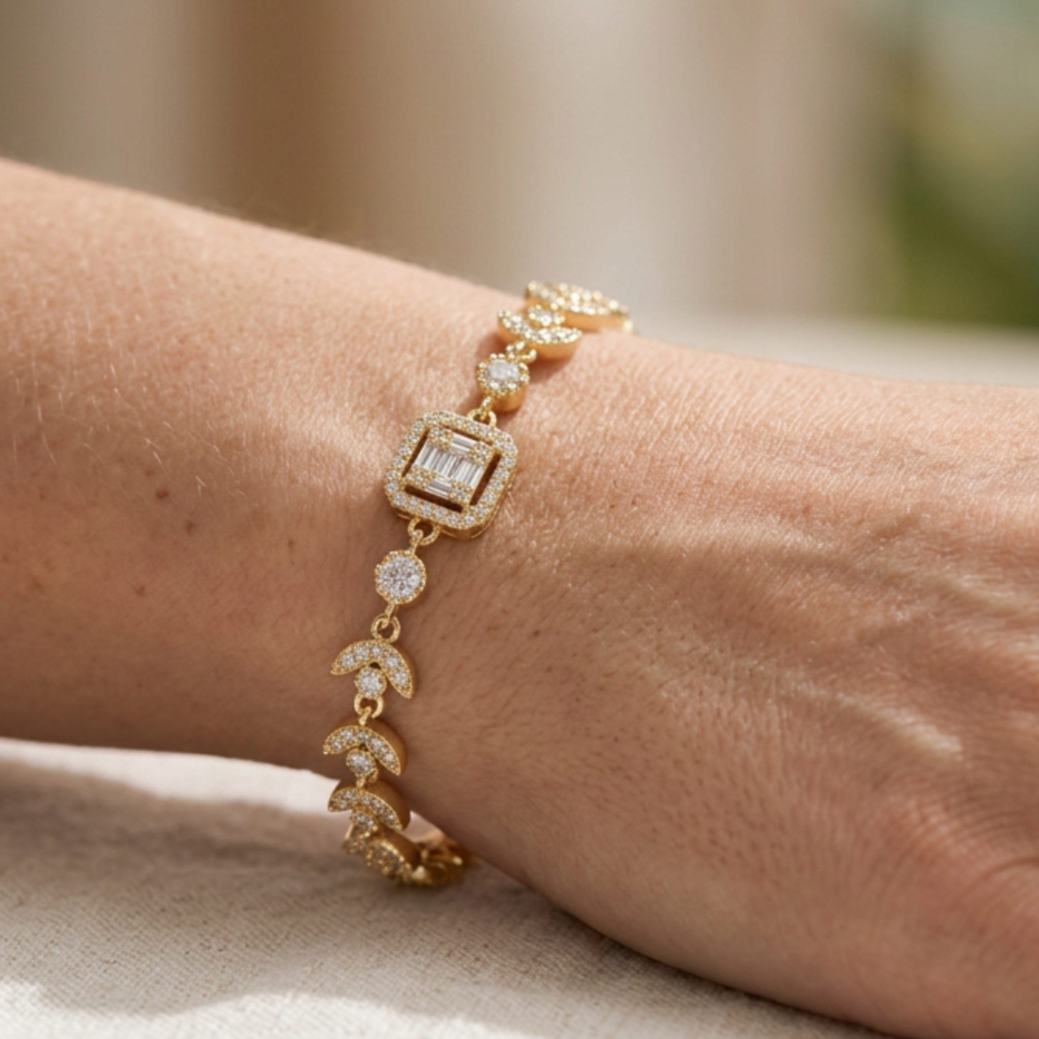 A gold bracelet with pavé-set clear stones and crescent moon motifs worn on a person's wrist.