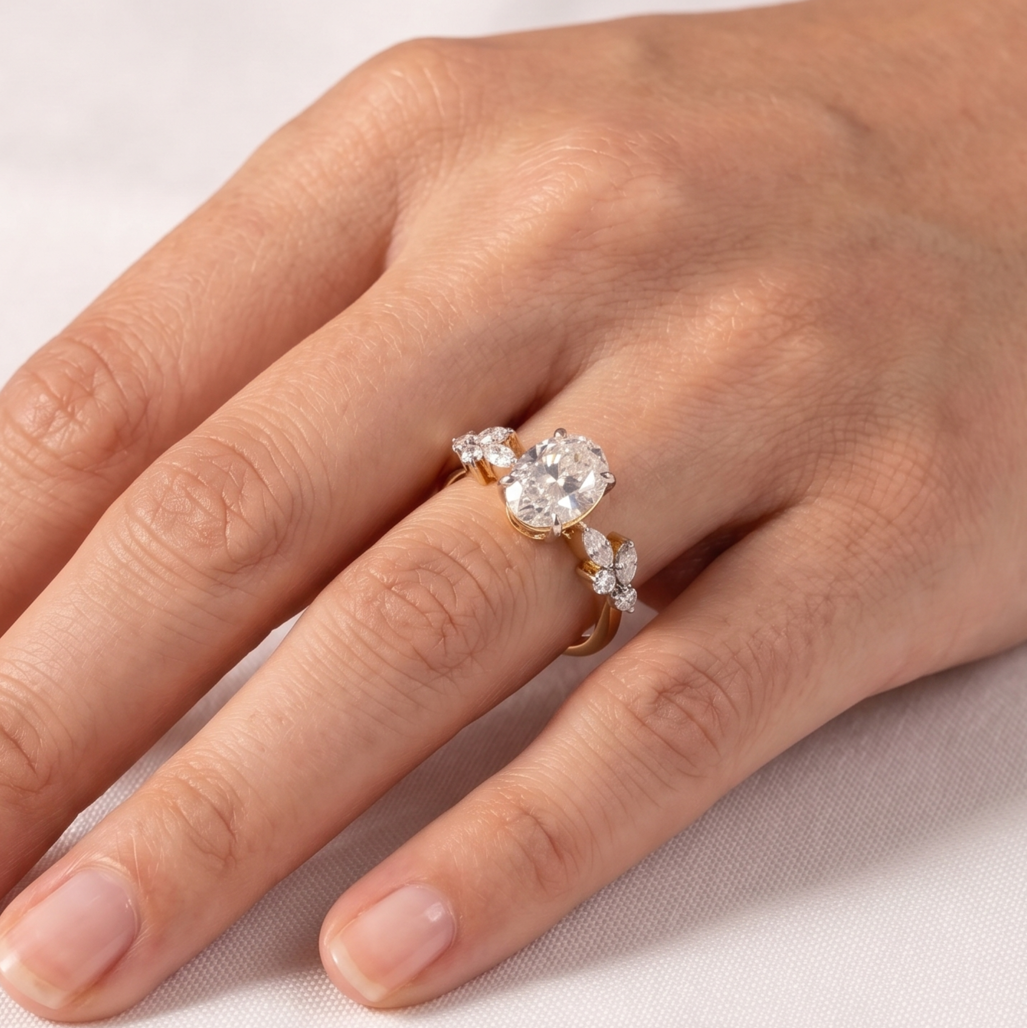 A close-up of a hand wearing a gold ring with a large clear center stone and smaller clear stones along the band, set against a soft light background.