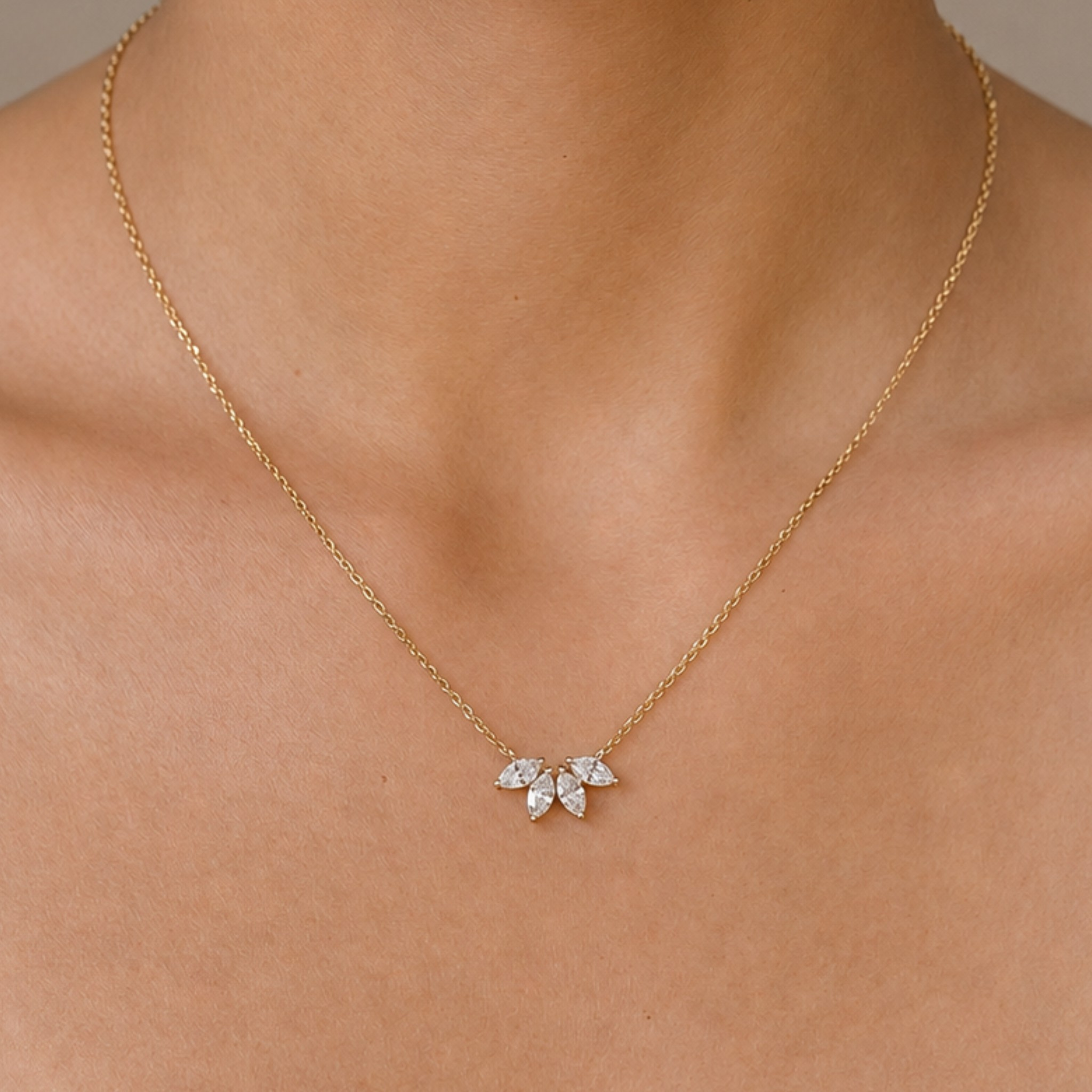 A delicate gold chain necklace with a small flower-shaped pendant set with clear gemstones, shown worn on a model's neck.