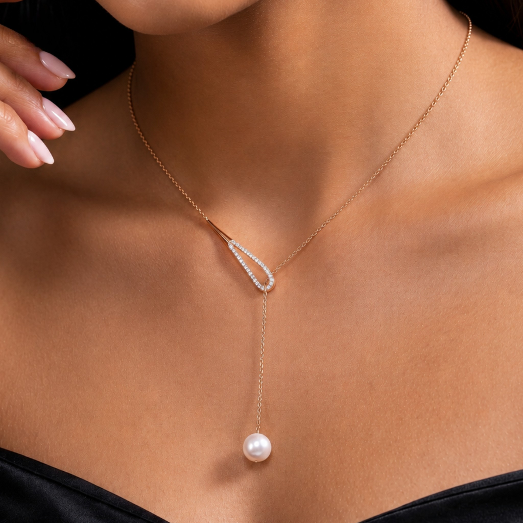 A close-up of a model wearing a delicate rose gold Y-necklace with a teardrop-shaped pavé setting and a single dangling pearl.