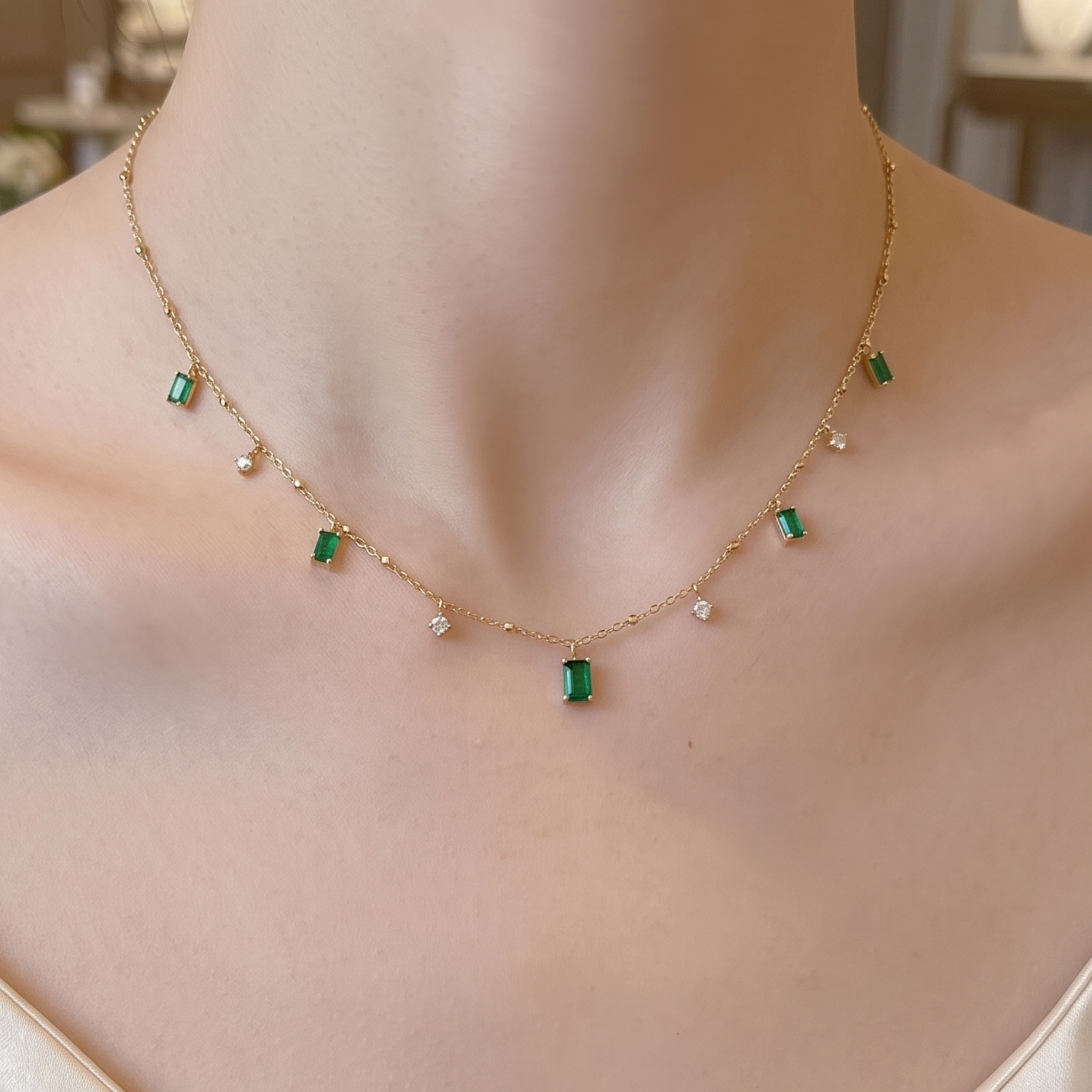 A delicate gold chain necklace with small green rectangular gemstones and tiny white pearl-like accents, shown worn on a model's neck.