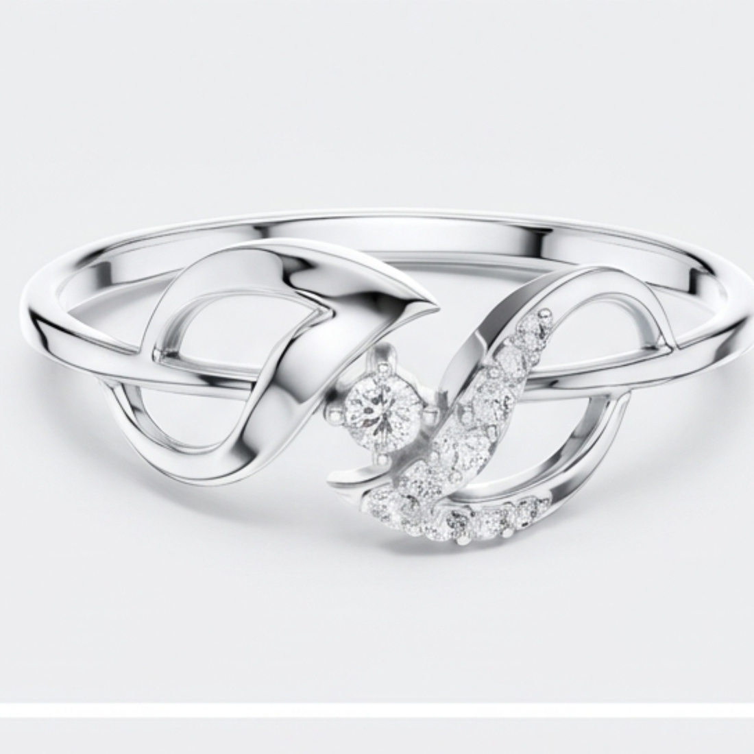 A silver ring featuring a polished infinity symbol design with a central round clear gemstone and a curved section paved with small clear stones, shown on a light gray background.