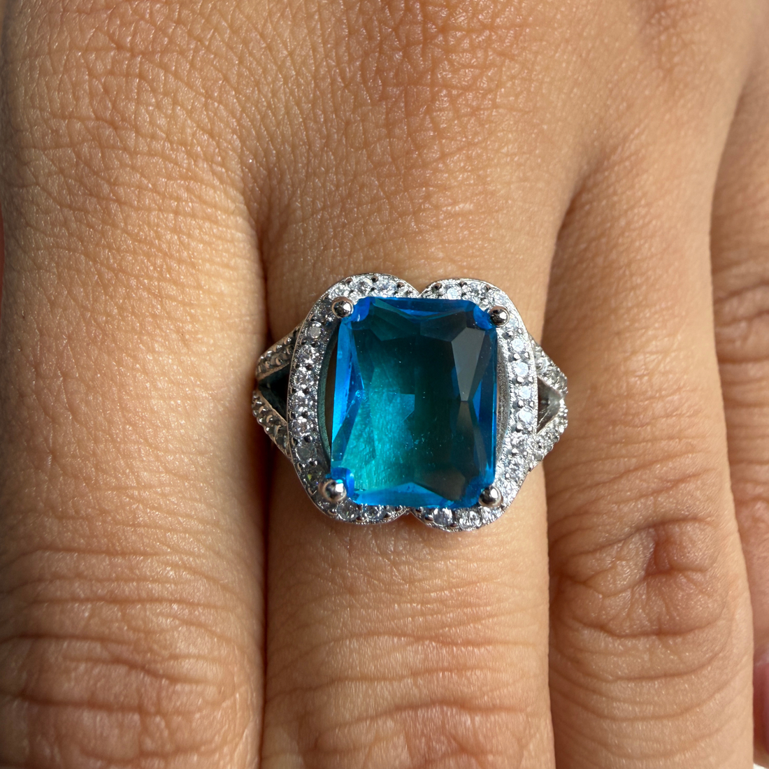 Blue emerald-cut gemstone and lab-grown diamond halo ring by Kiashaa Jewellery.
