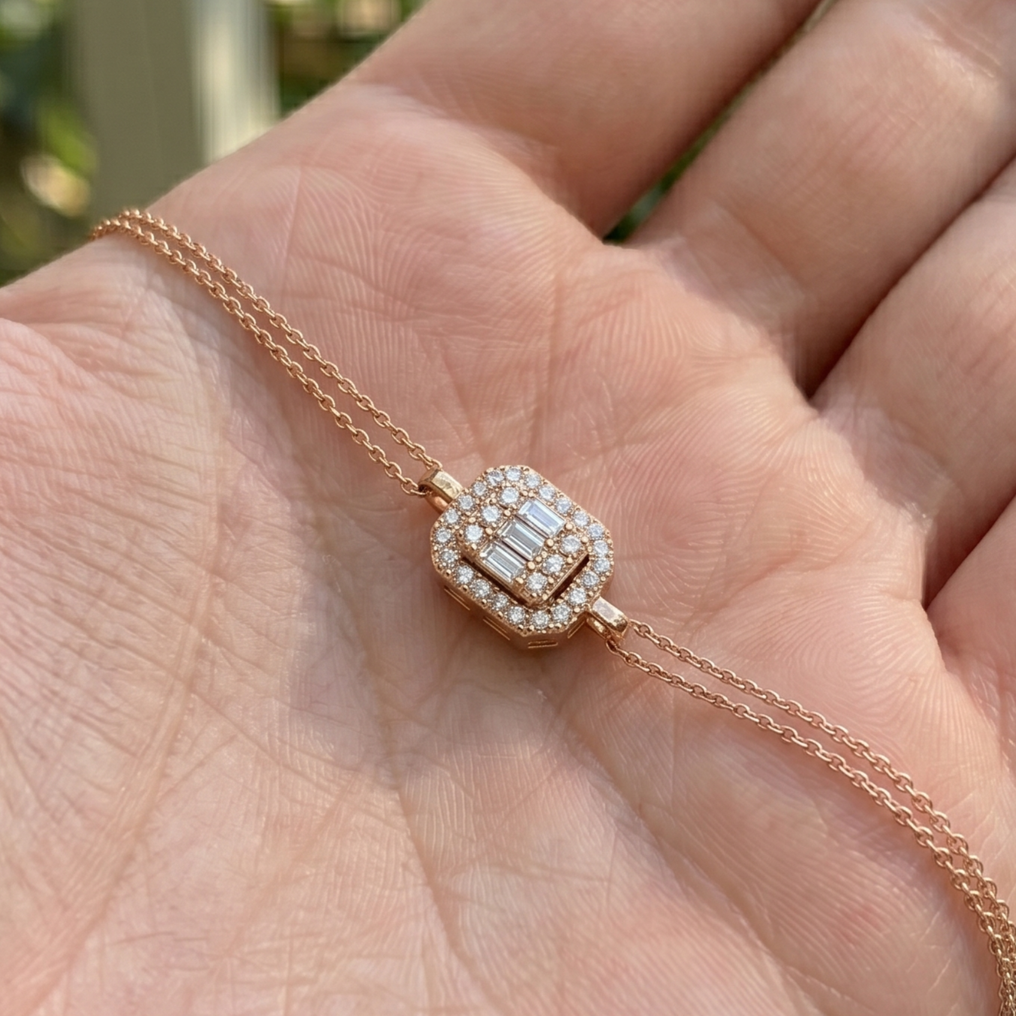 A close-up of a rose gold necklace with a diamond-encrusted pendant resting on a person's palm.