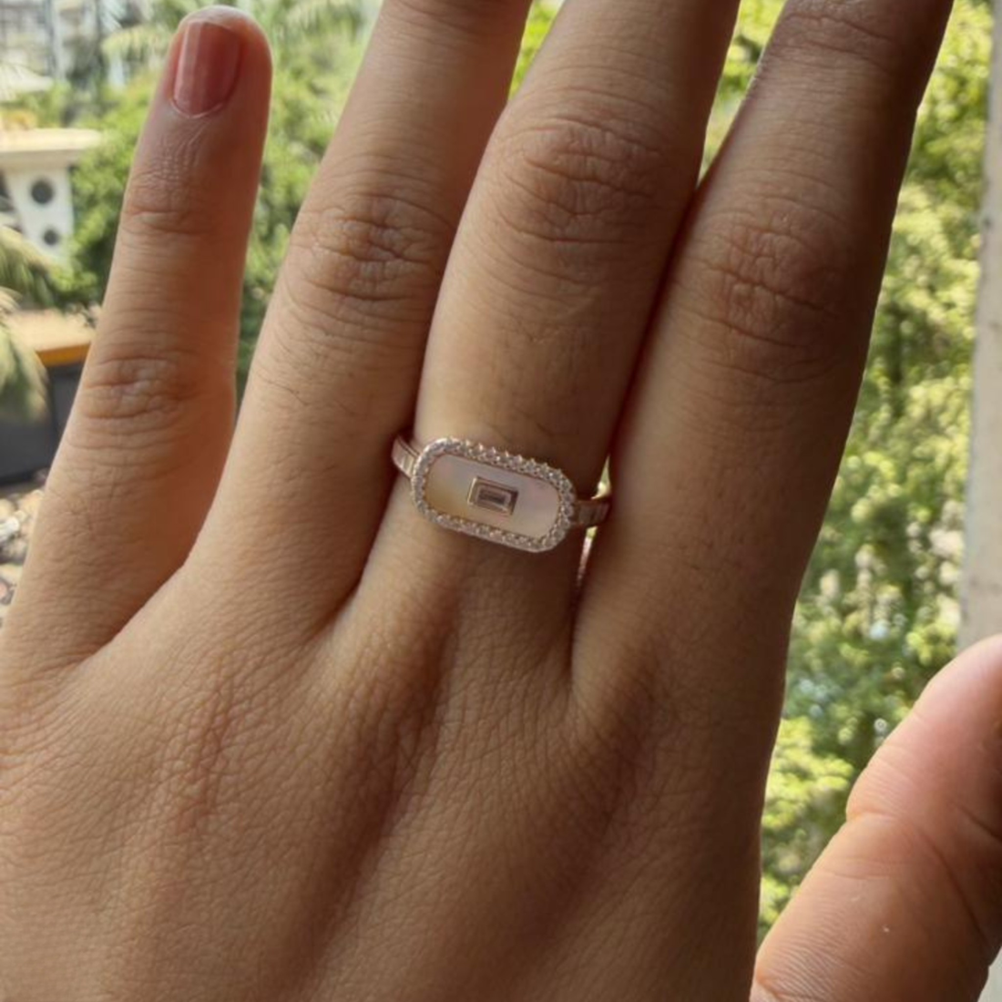 Geometric diamond ring featuring a luminous elongated mother-of-pearl center.