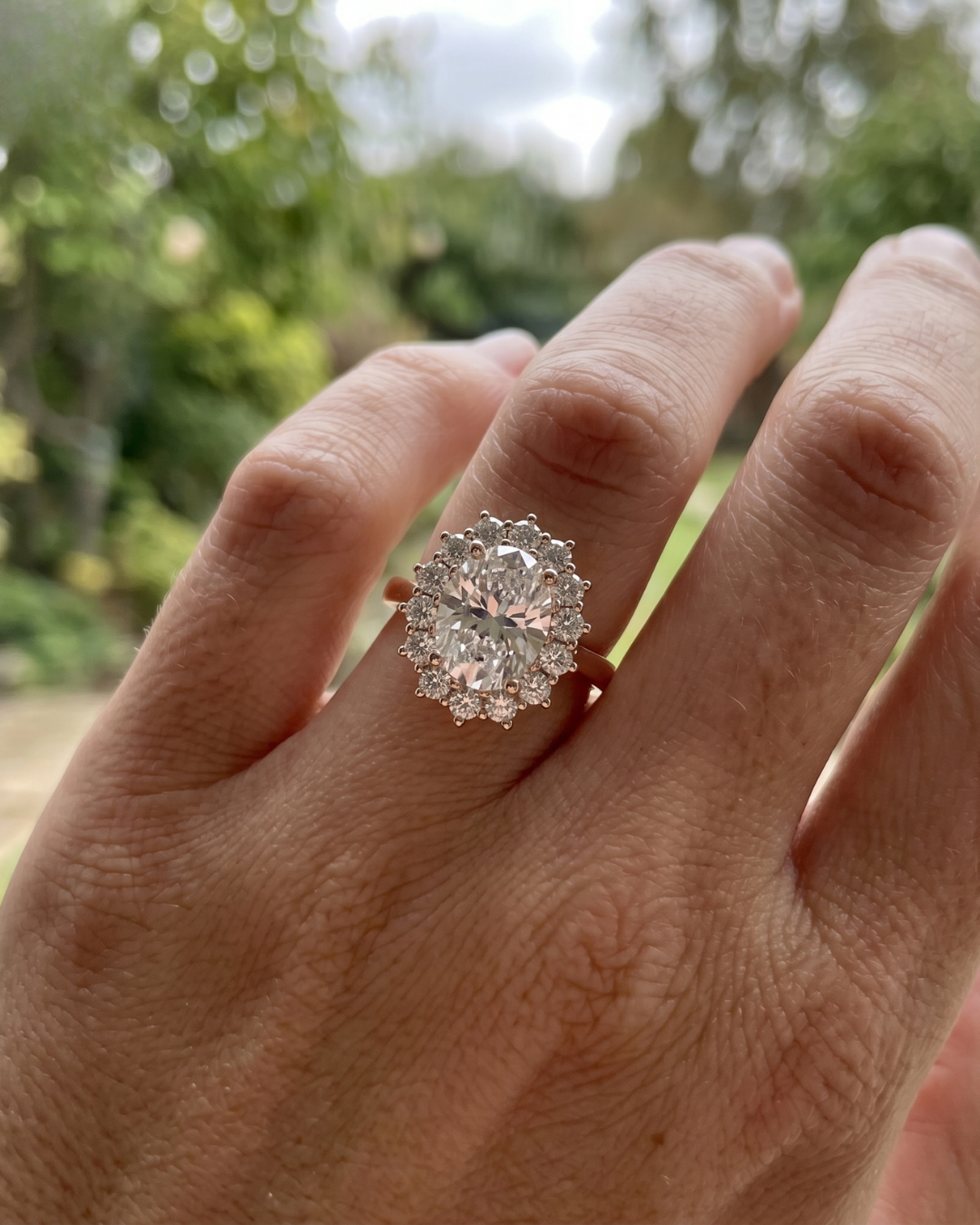 Rose gold oval lab-grown diamond engagement ring by Kiashaa Jewellery featuring a sparkling round floral halo.
