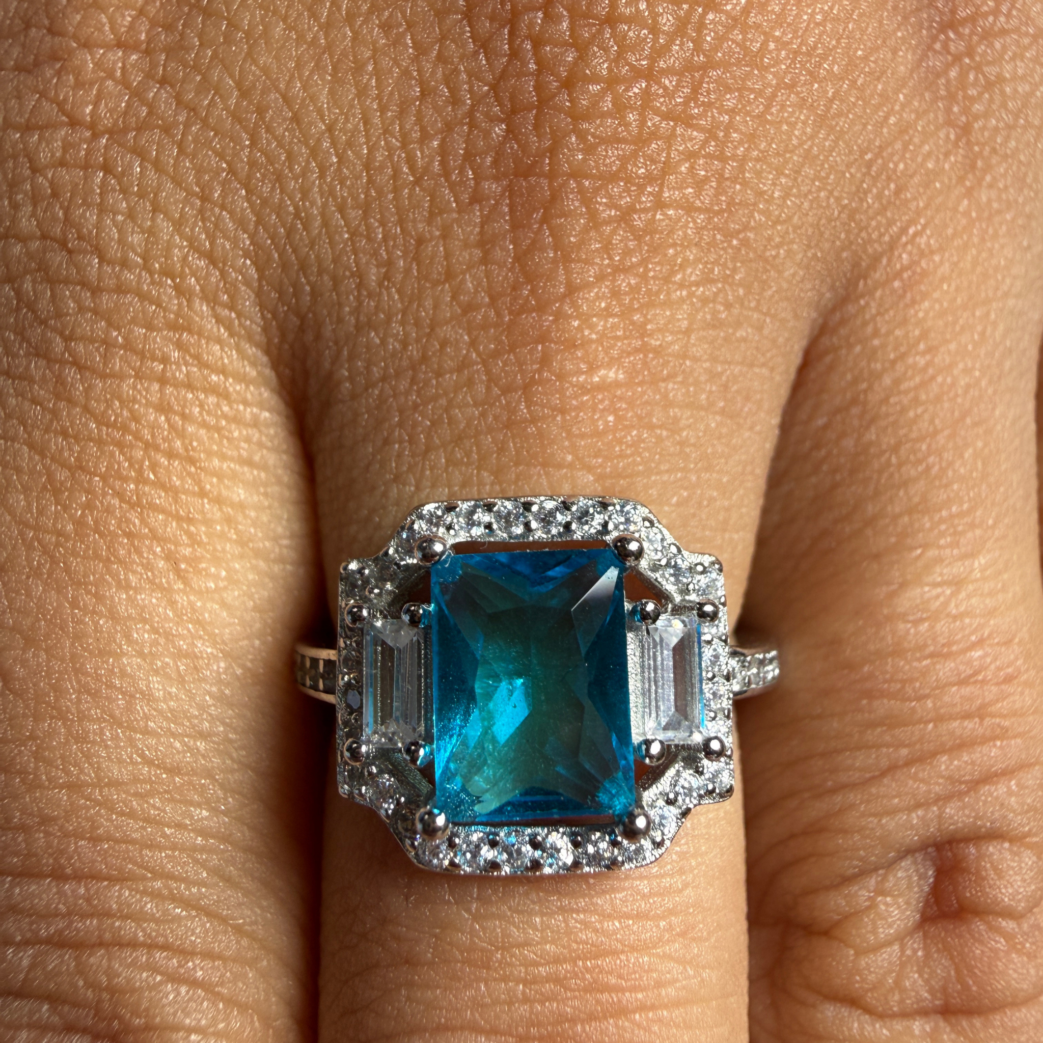 Blue emerald-cut gemstone and lab-grown diamond halo ring by Kiashaa Jewellery.