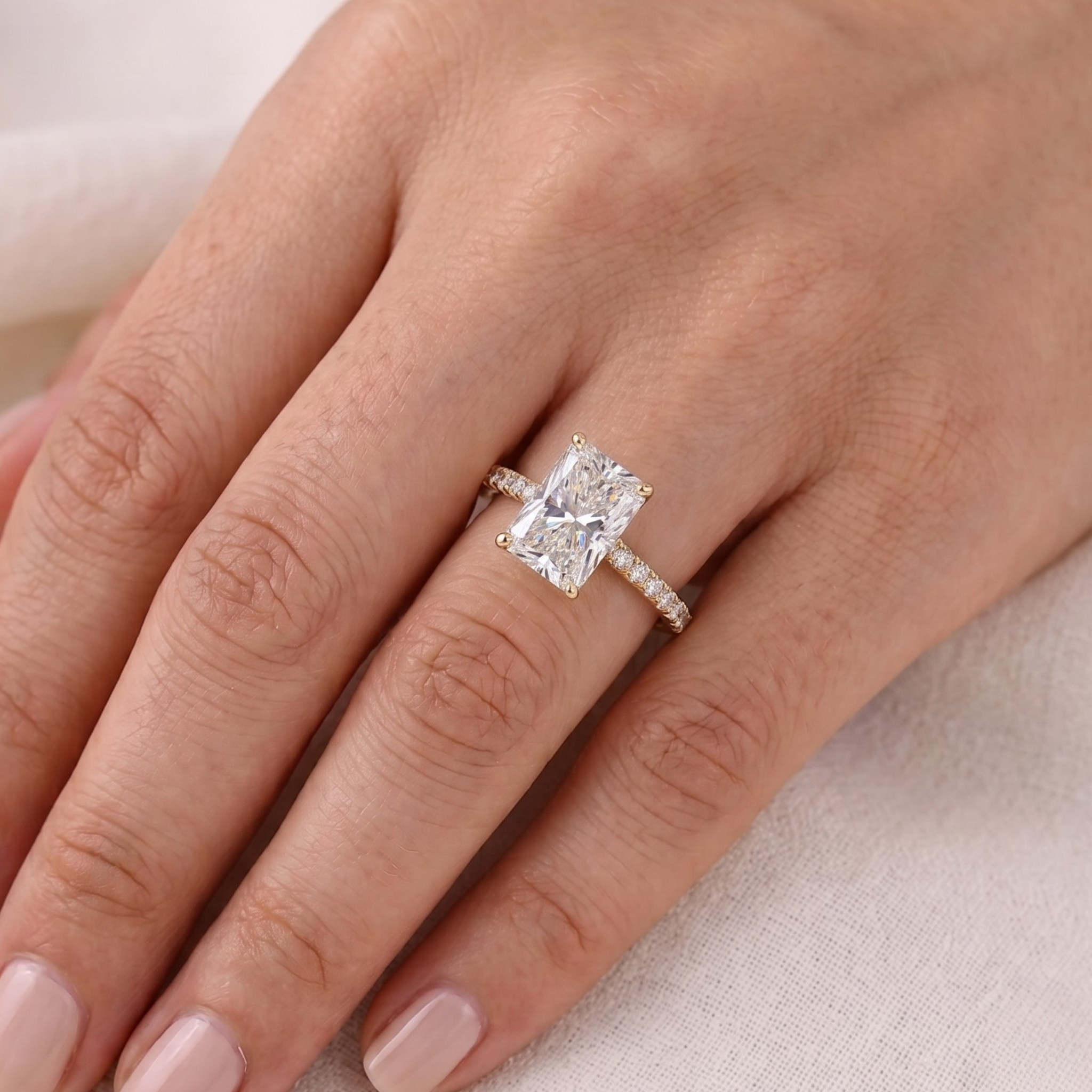 Four-prong emerald-cut diamond ring with sparkling gold shoulders