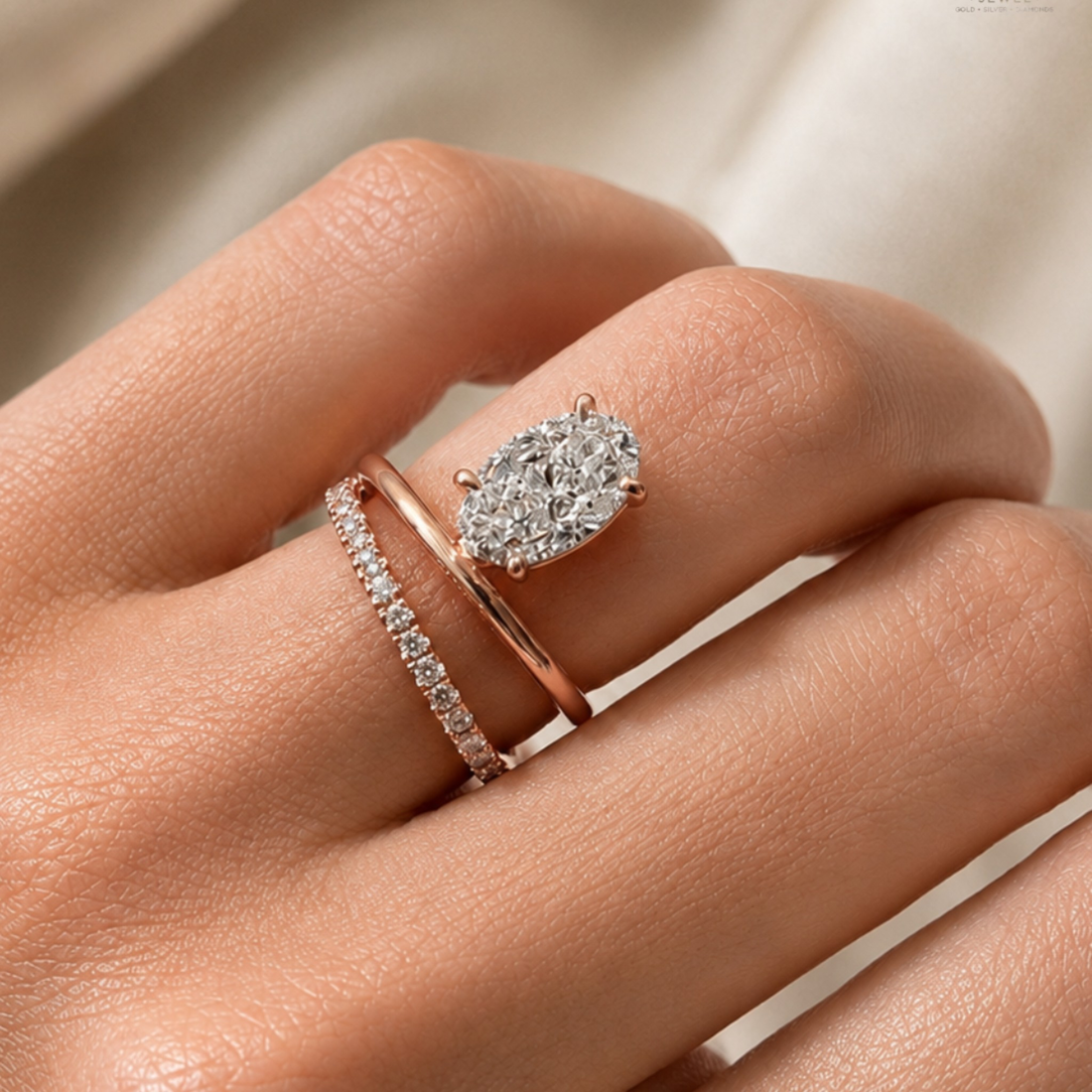 A close-up of a hand wearing two rings: a rose gold band with a marquise-cut diamond cluster and a second rose gold band with a row of small round diamonds.