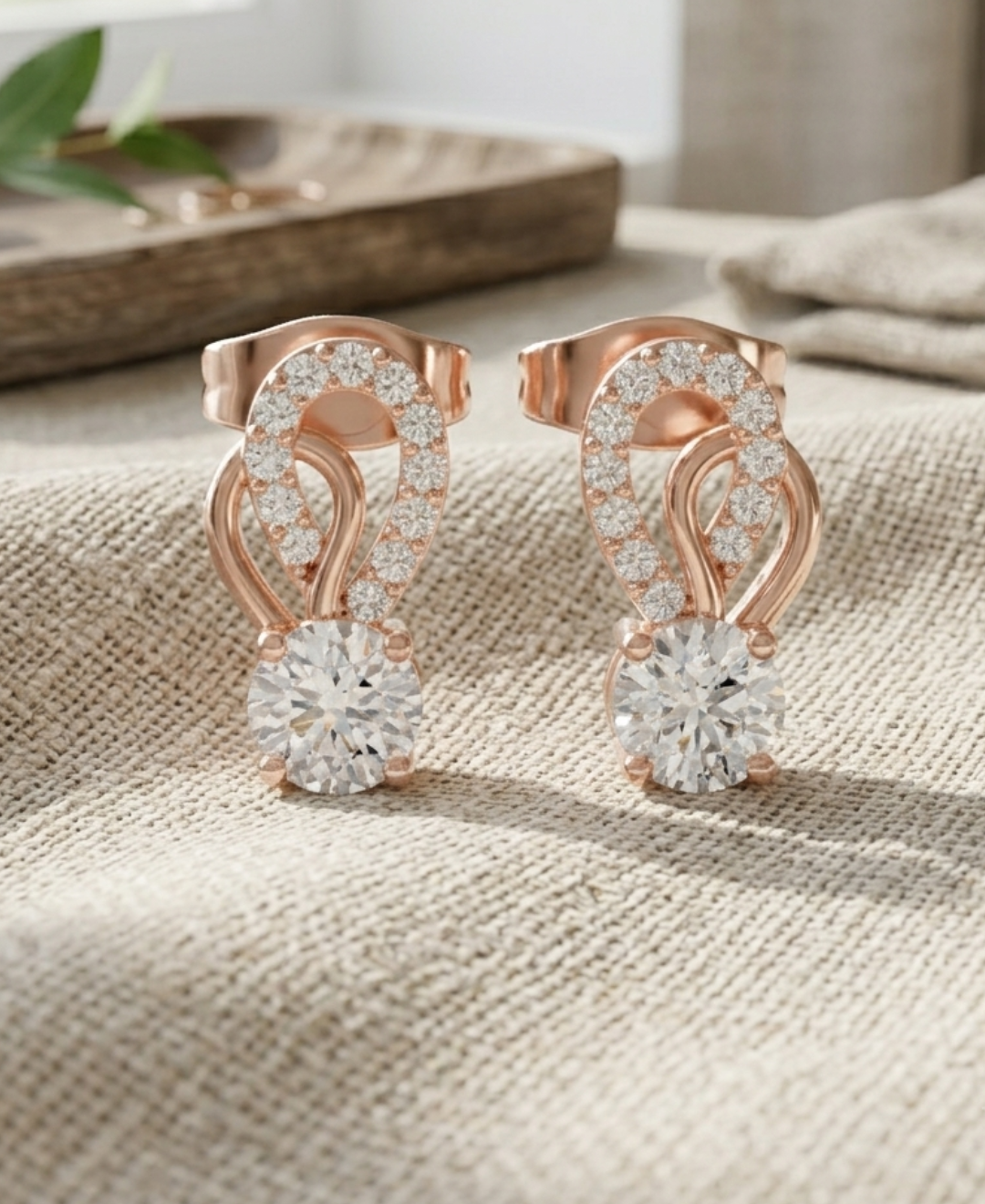 Rose gold diamond stud earrings featuring round focal stones and pavé-set teardrop loops.