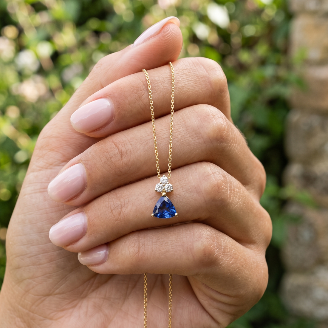 0.96 CTW blue trillion pendant necklace with a 6 mm center stone and three round diamond accents.
