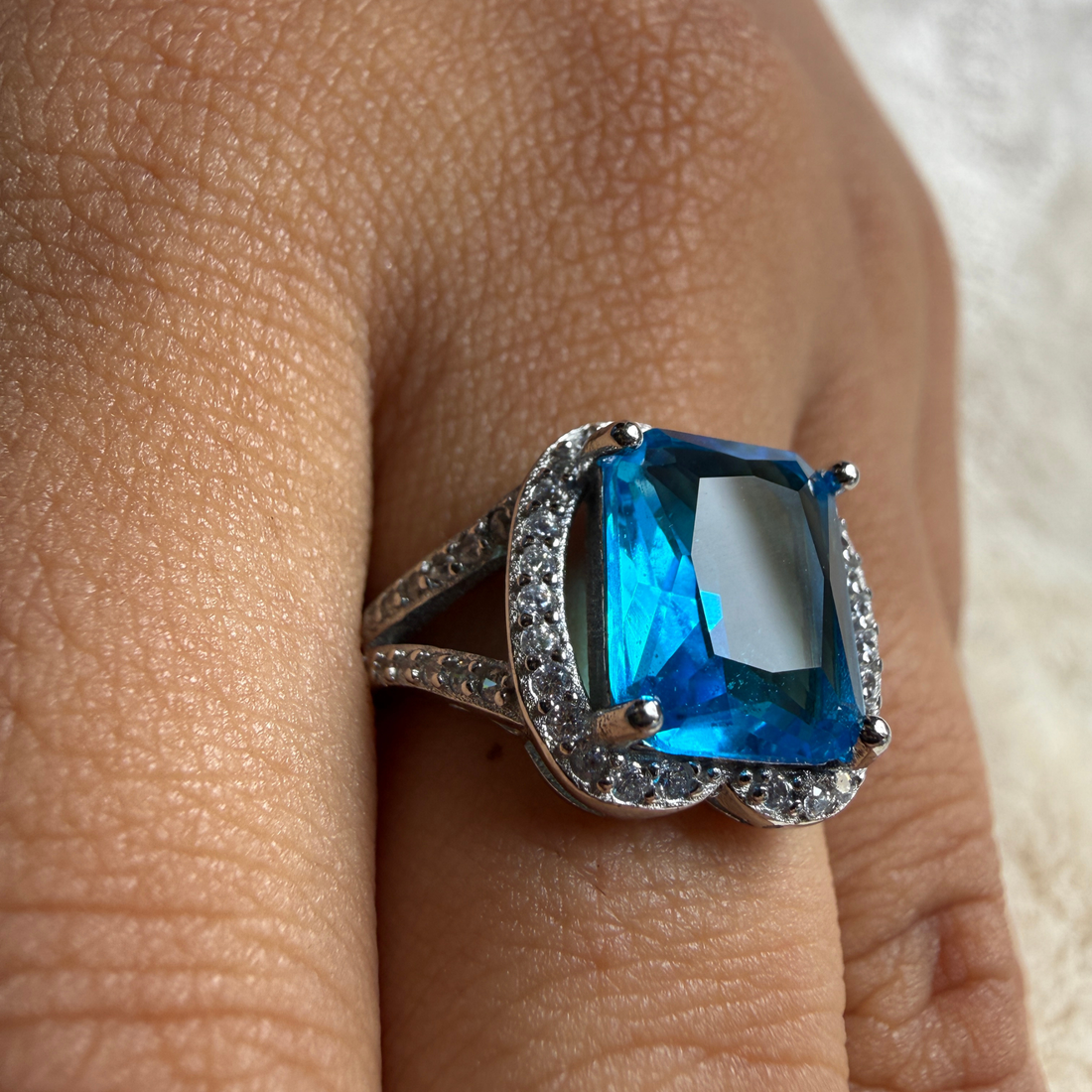 Blue emerald-cut gemstone and lab-grown diamond halo ring by Kiashaa Jewellery.