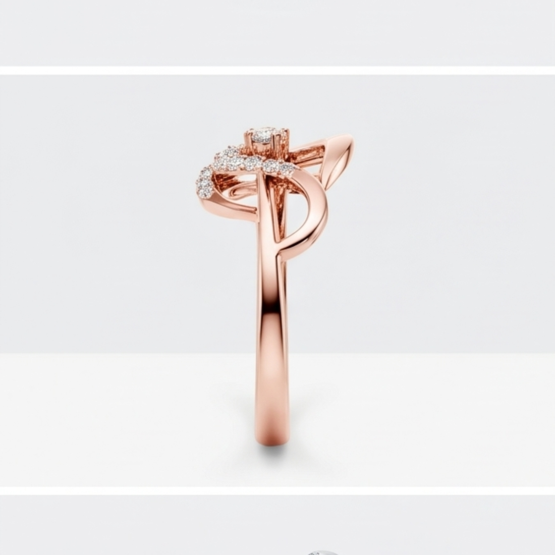A rose gold ring with a curved, leaf-like top set with small clear stones, shown on a light gray background.