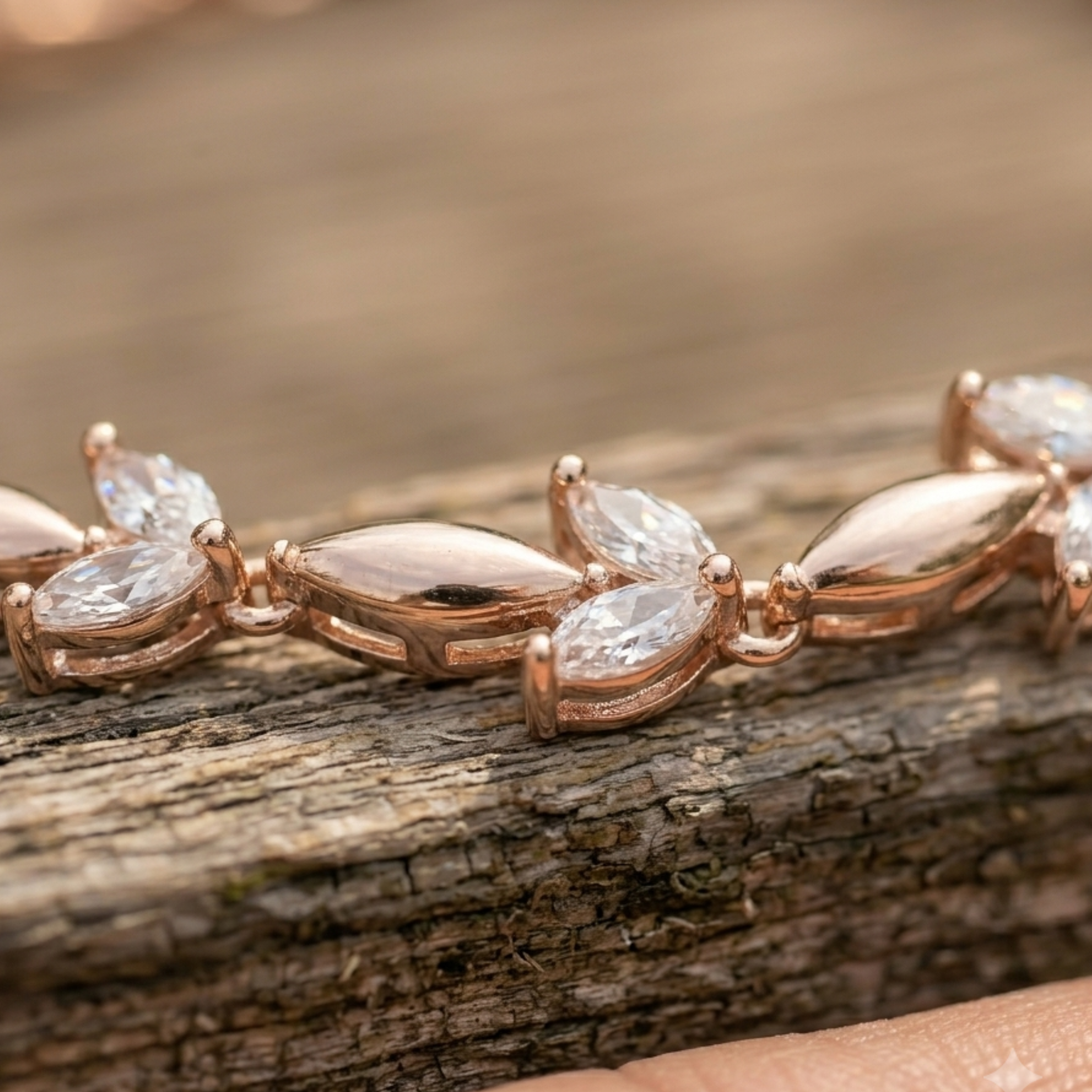 Rose gold jewelry featuring marquise-cut clear gemstones set in a polished metal, shown resting on a textured wooden surface.