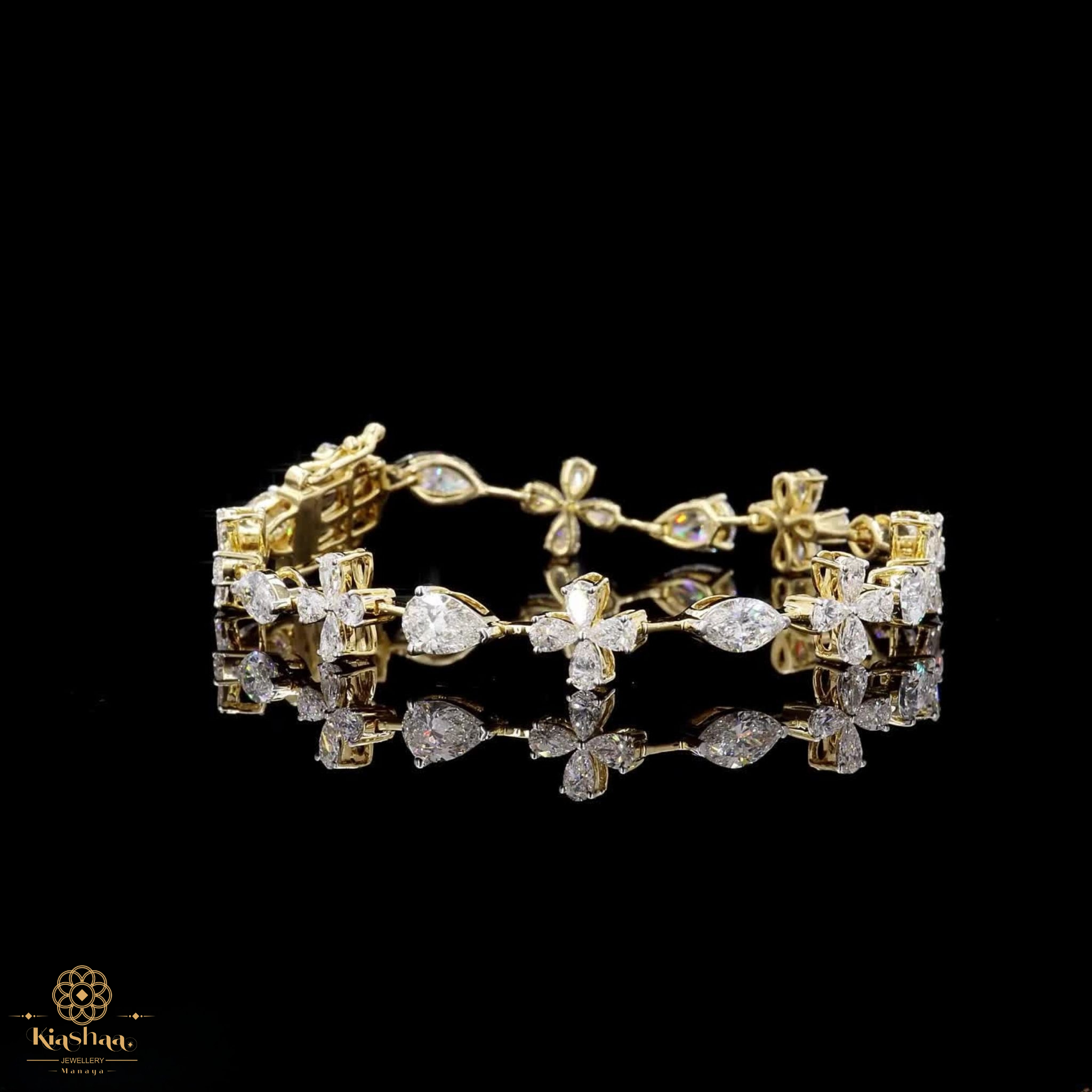 A gold bracelet adorned with clear gemstones in floral and marquise-shaped settings, displayed on a reflective black surface against a black background. A small 'Kavuti' brand logo is visible in the bottom-left corner.