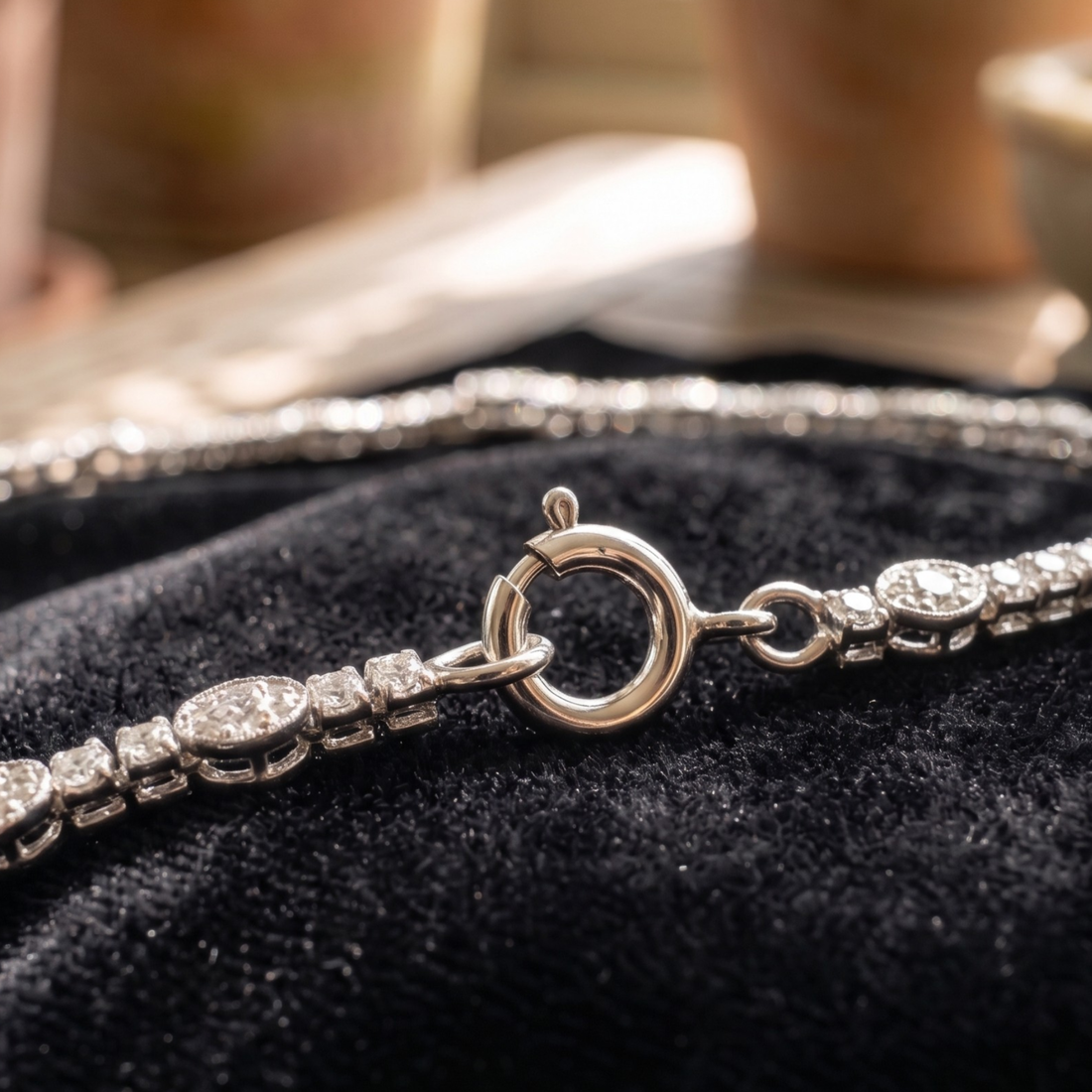 A close-up of a silver-toned tennis bracelet with round-cut stones, resting on a black velvet jewelry display.