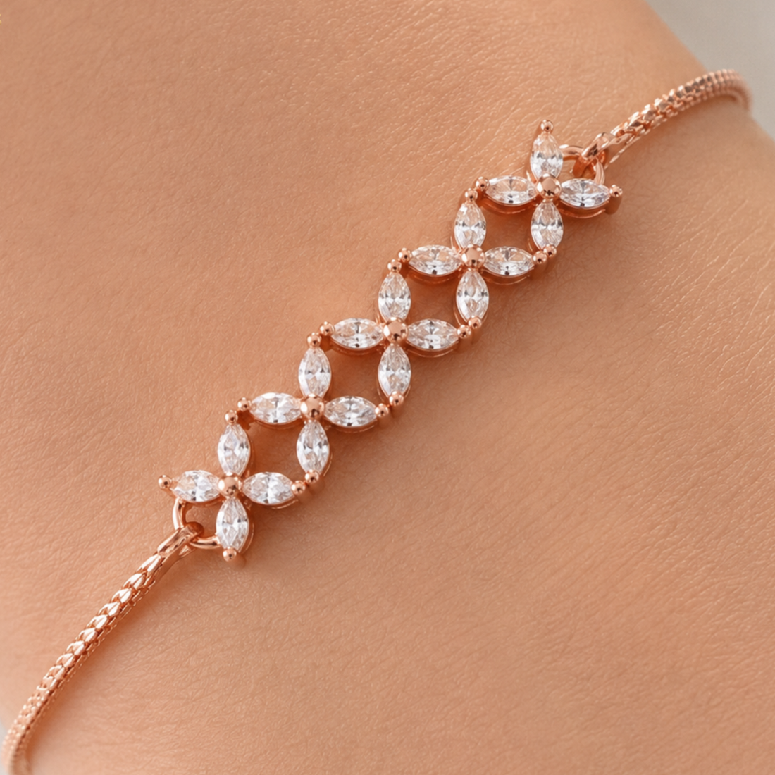 Rose gold bracelet with marquise-cut clear stones arranged in a floral pattern, shown worn on a wrist.