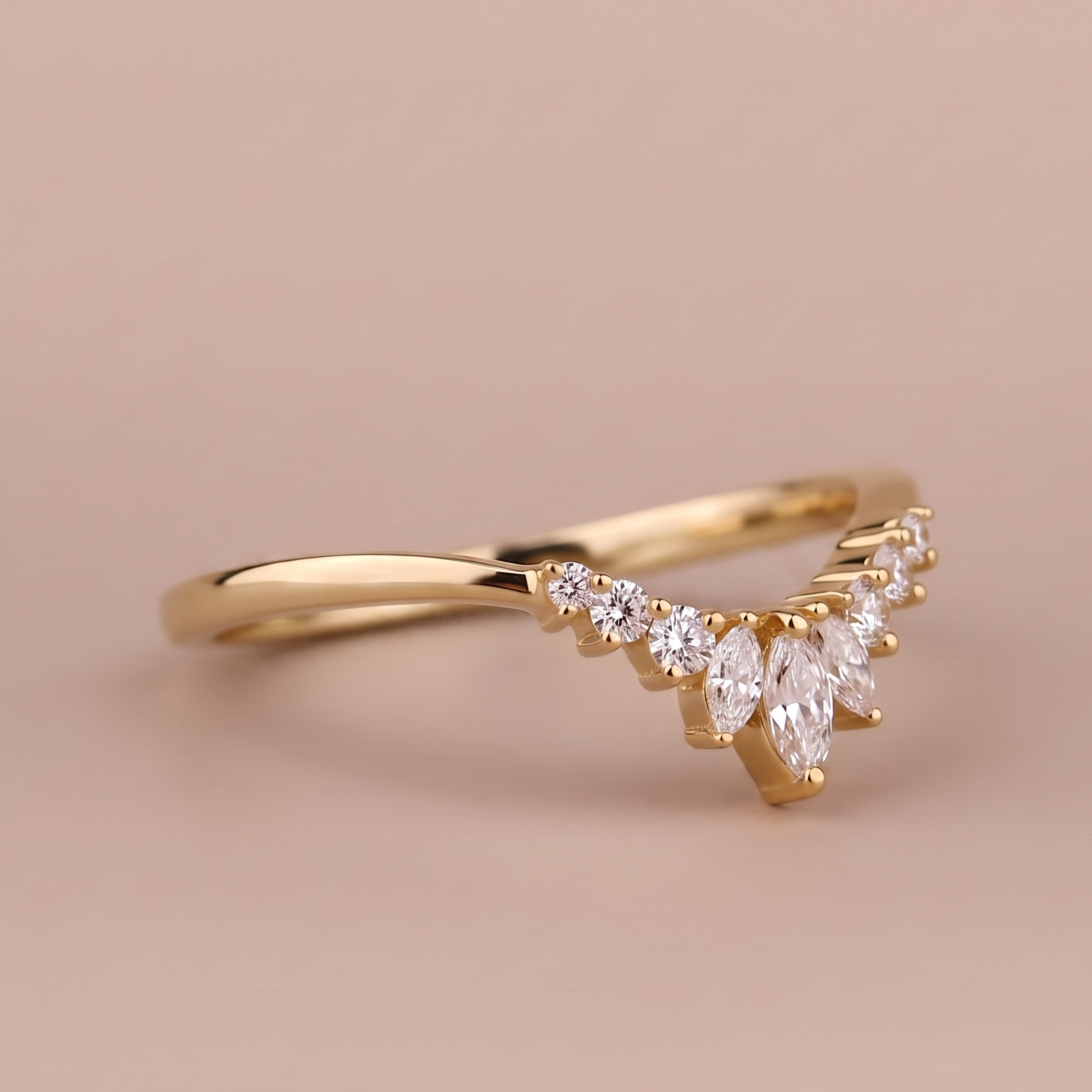A gold ring with a marquise-cut diamond center and smaller round diamonds along the band, set against a solid warm beige background.