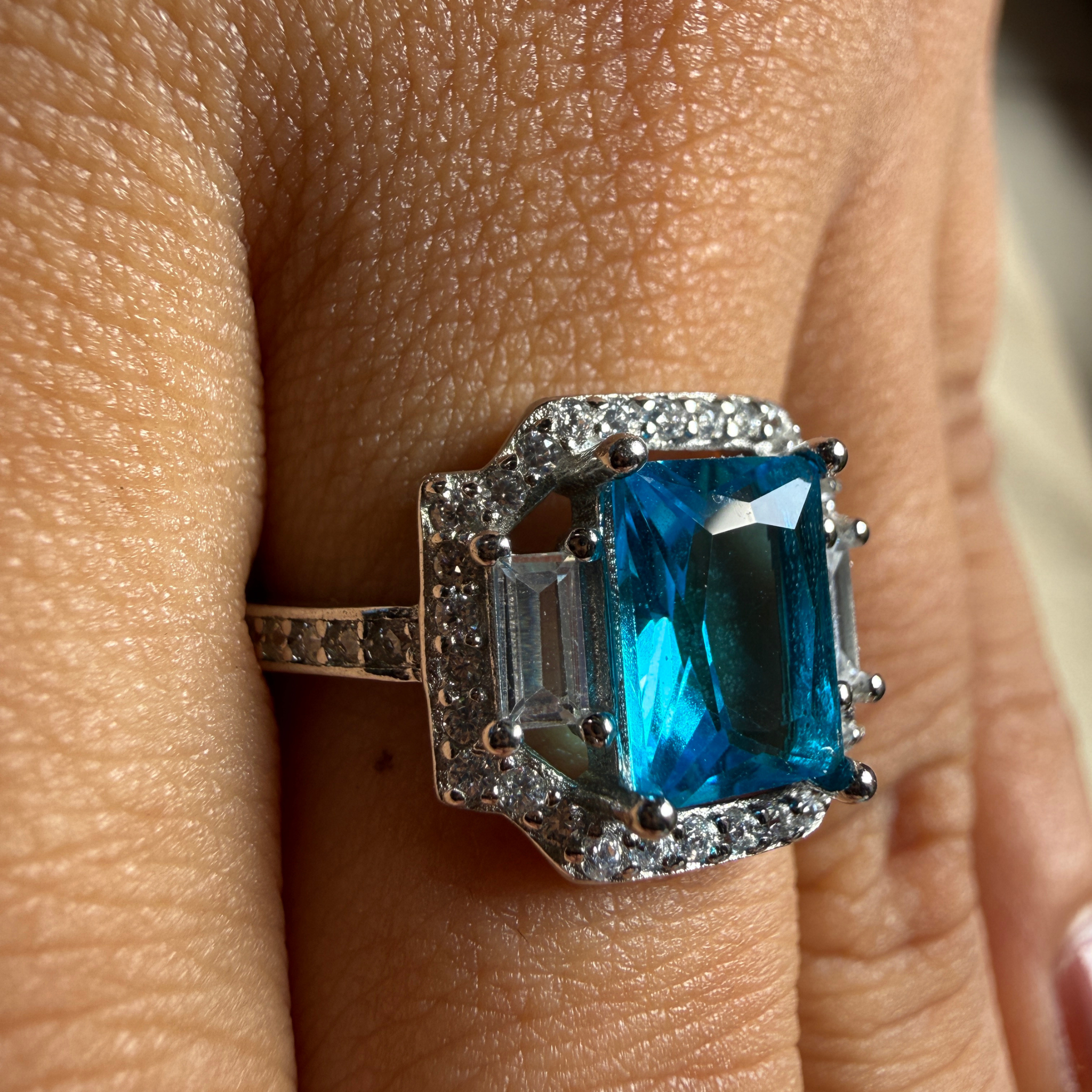 Blue emerald-cut gemstone and lab-grown diamond halo ring by Kiashaa Jewellery.