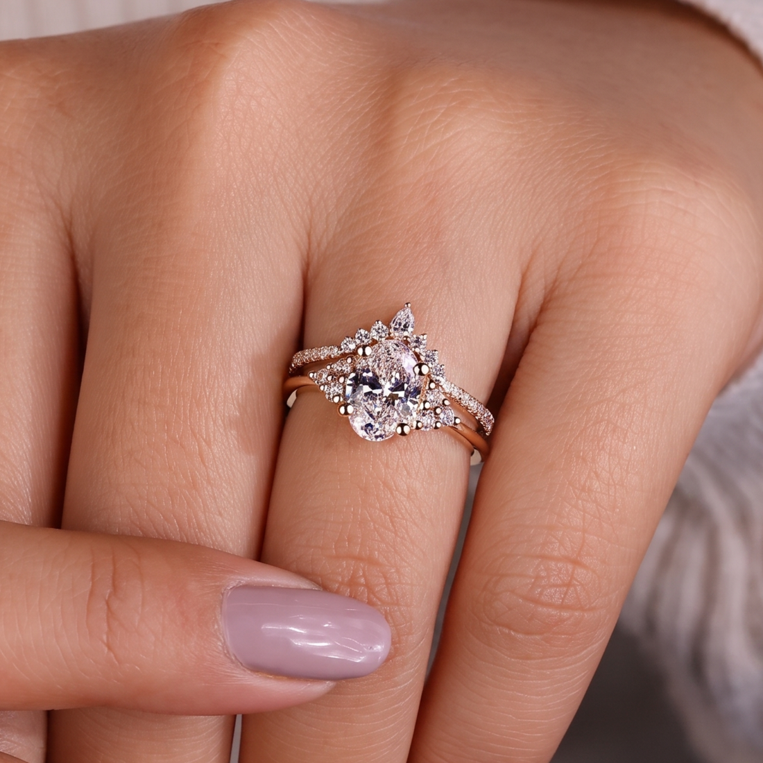A close-up of a hand wearing a rose gold ring with a clear central gemstone and surrounding smaller stones.