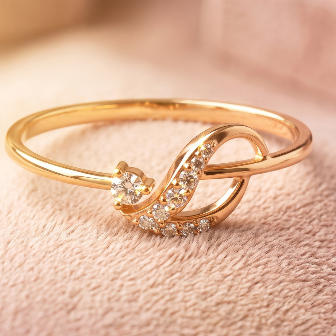 A gold ring with a stylized intertwined loop design, featuring a single round clear gemstone and a row of small clear stones, displayed on a soft beige textured surface.