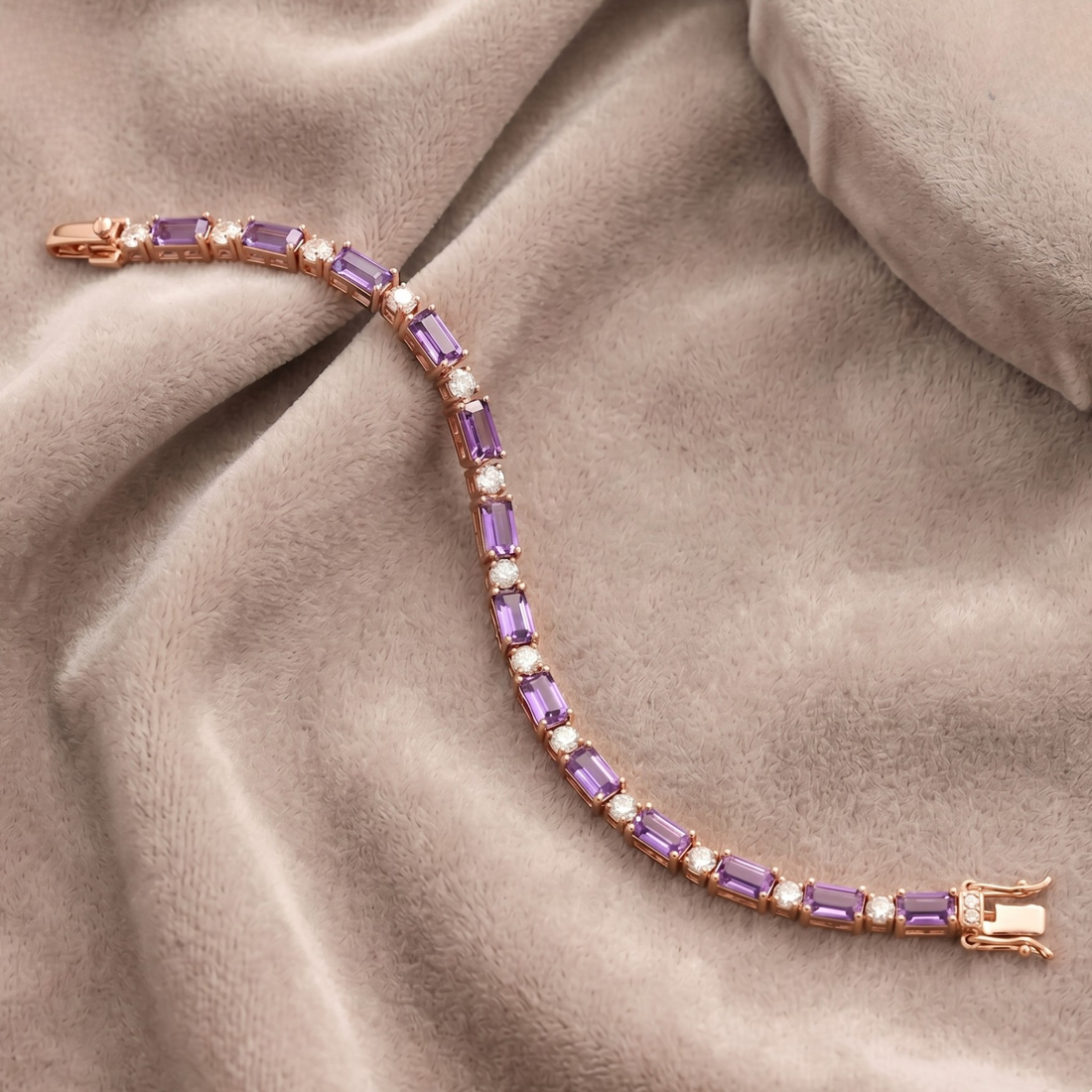 A rose gold tennis bracelet with rectangular purple amethyst and round white pearl accents, displayed on a draped beige satin fabric.