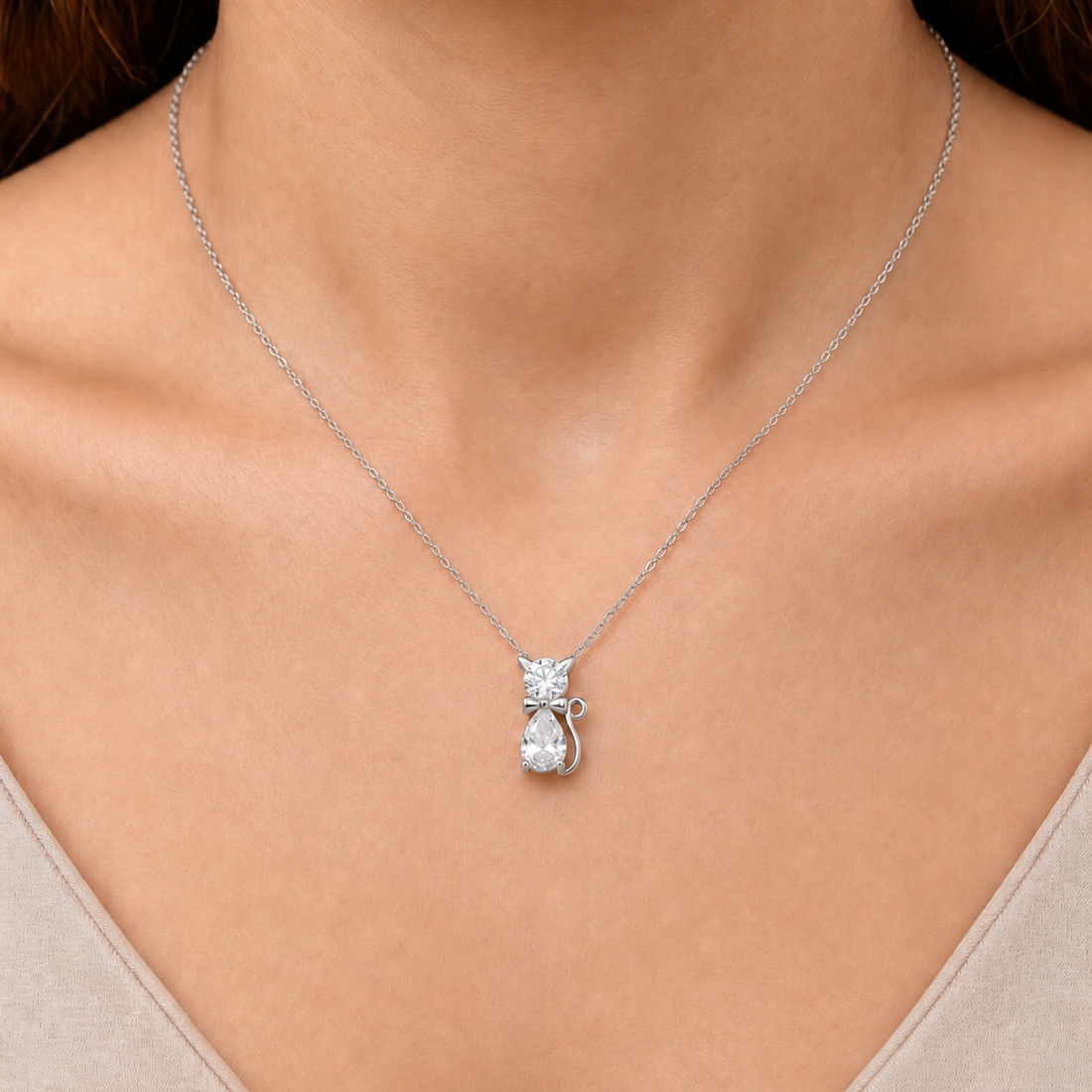 A silver-toned necklace with a small pendant featuring clear gemstones, shown worn on a model's neck.