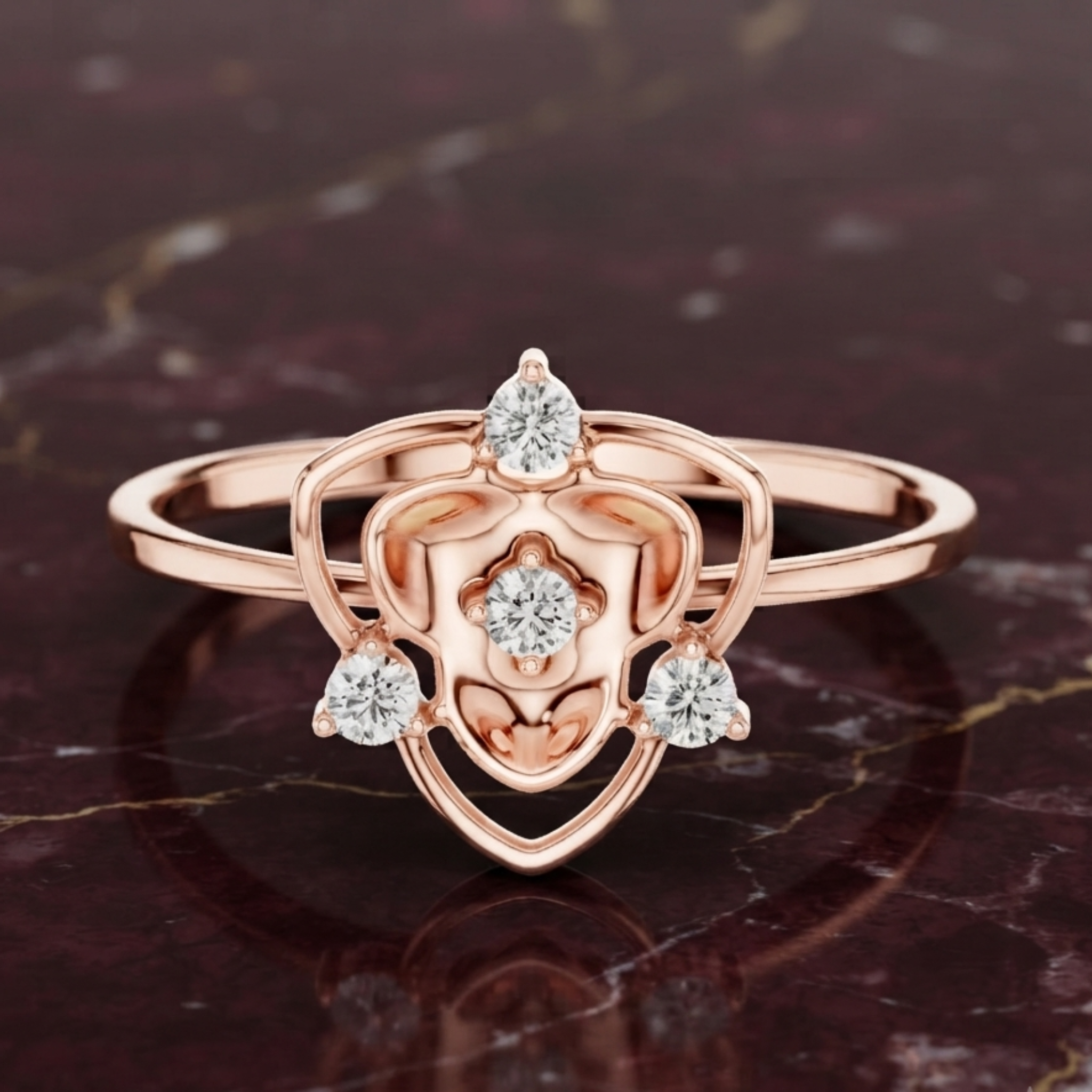 Rose gold ring with a heart-shaped openwork design and four clear gemstones, displayed on a dark marbled surface.