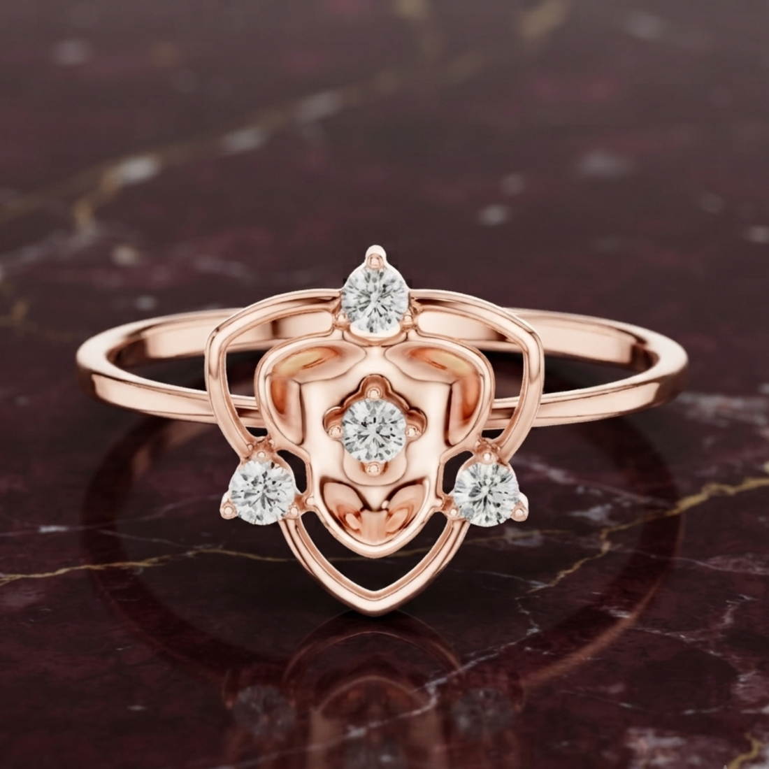 Rose gold ring with a heart-shaped openwork design and four clear gemstones, displayed on a dark marbled surface.