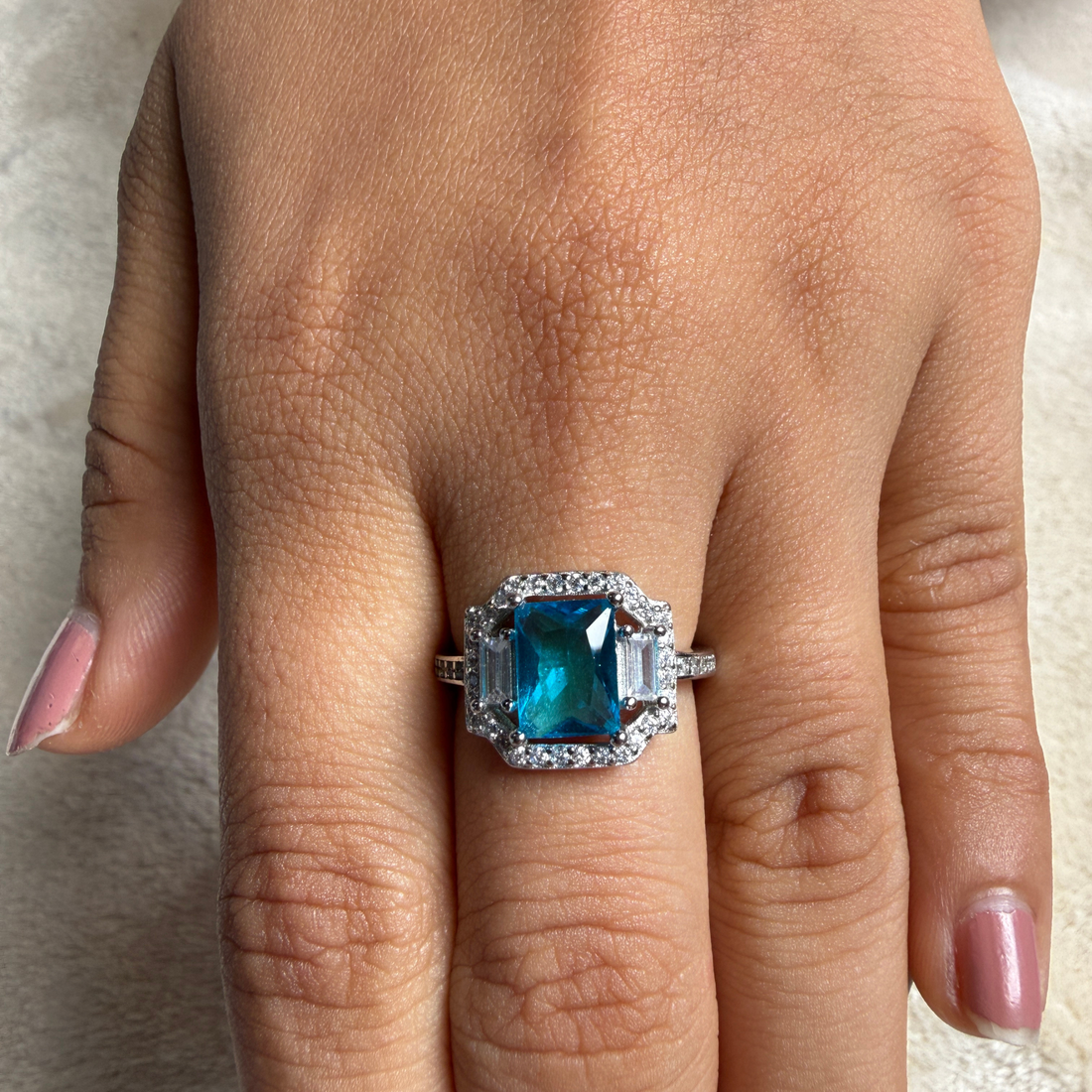 Blue emerald-cut gemstone and lab-grown diamond halo ring by Kiashaa Jewellery.